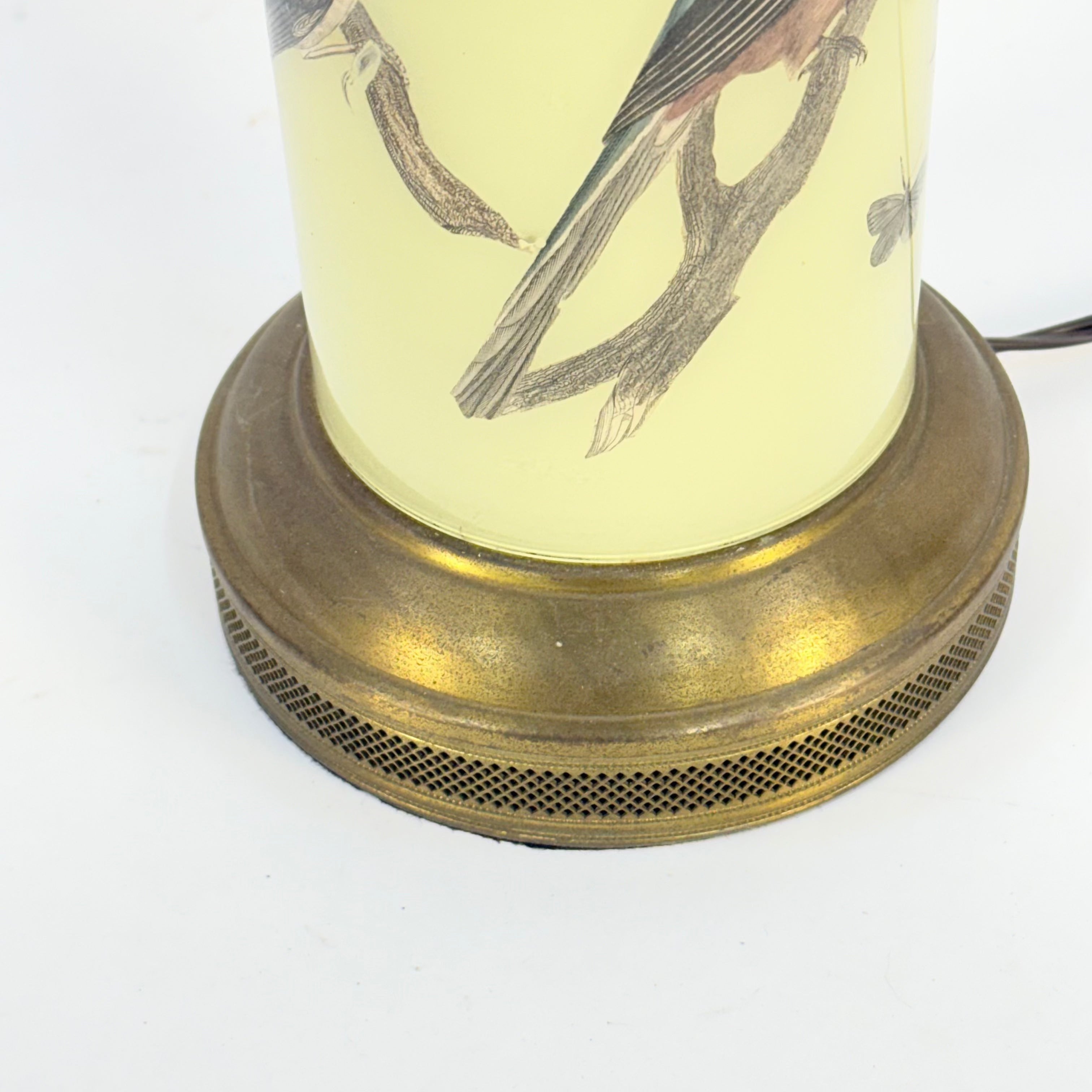 Vintage-style lamp with brass base and bird illustration on a white background