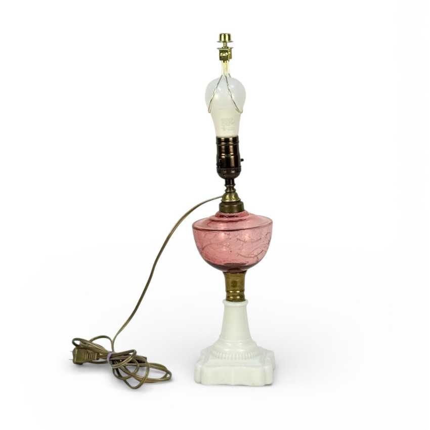 Vintage-style table lamp with pink glass base and white marble top on a white background