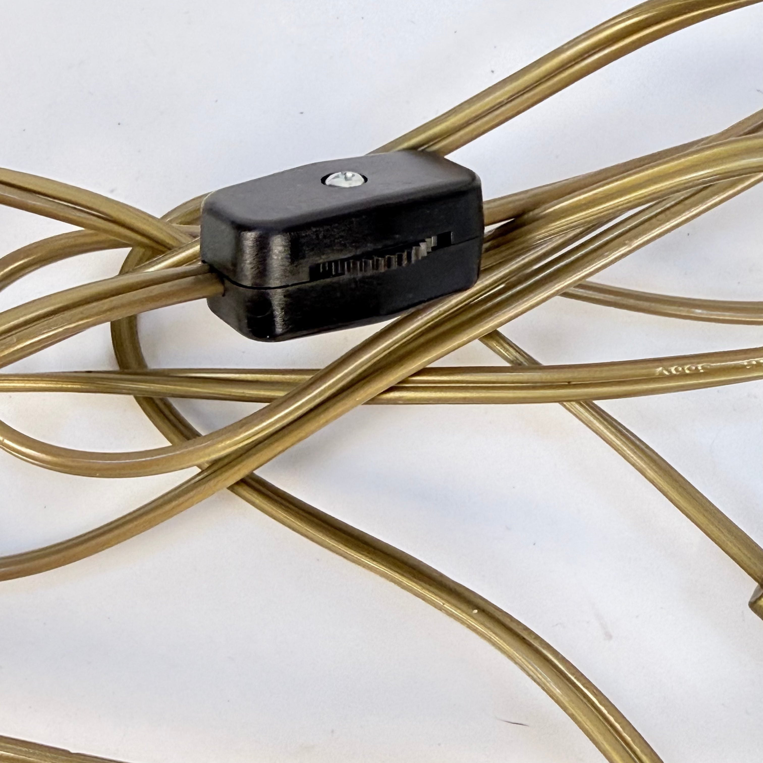 Black electronic component on a metal whisk against a white background
