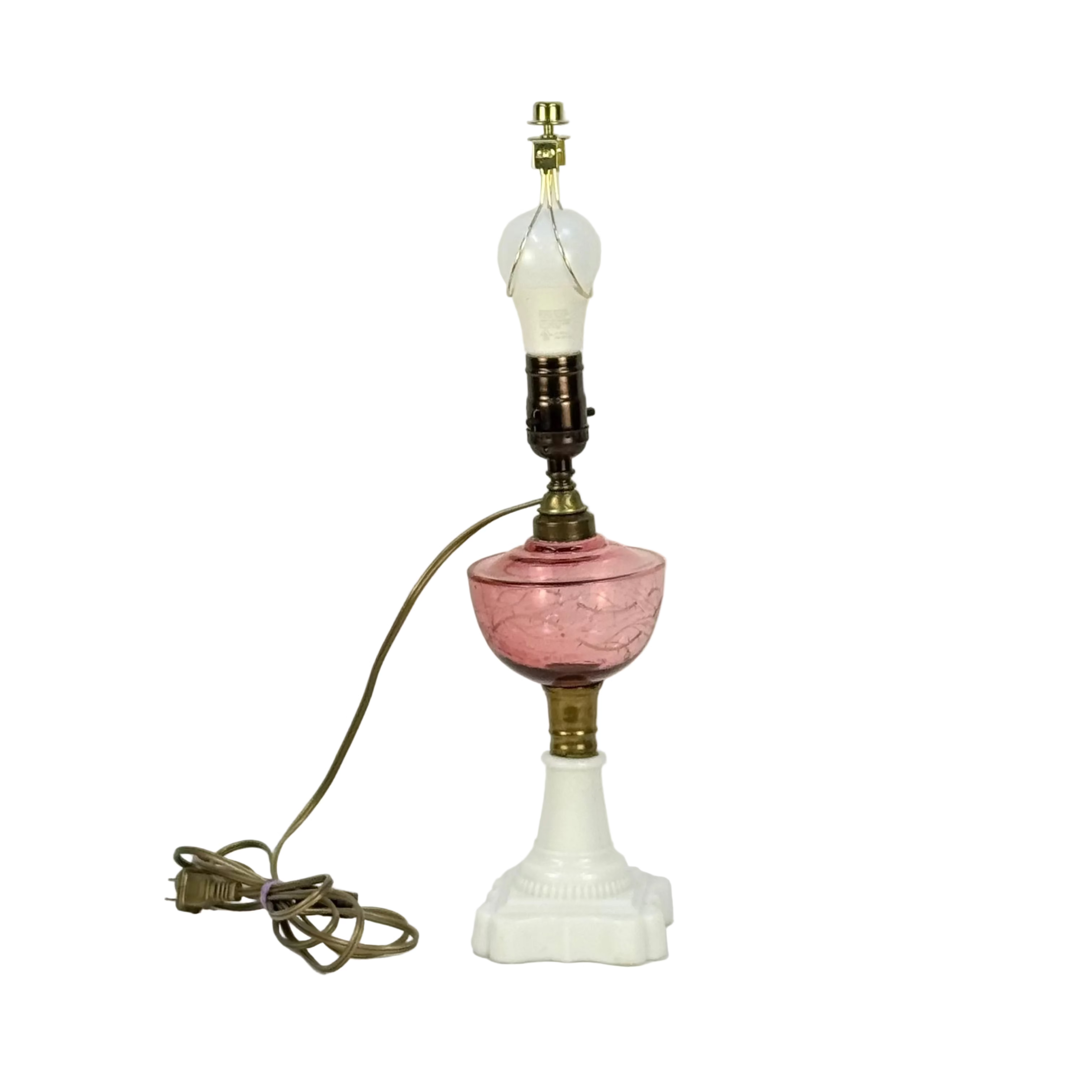 Vintage-style lamp with pink glass base and white shade on a light gray background