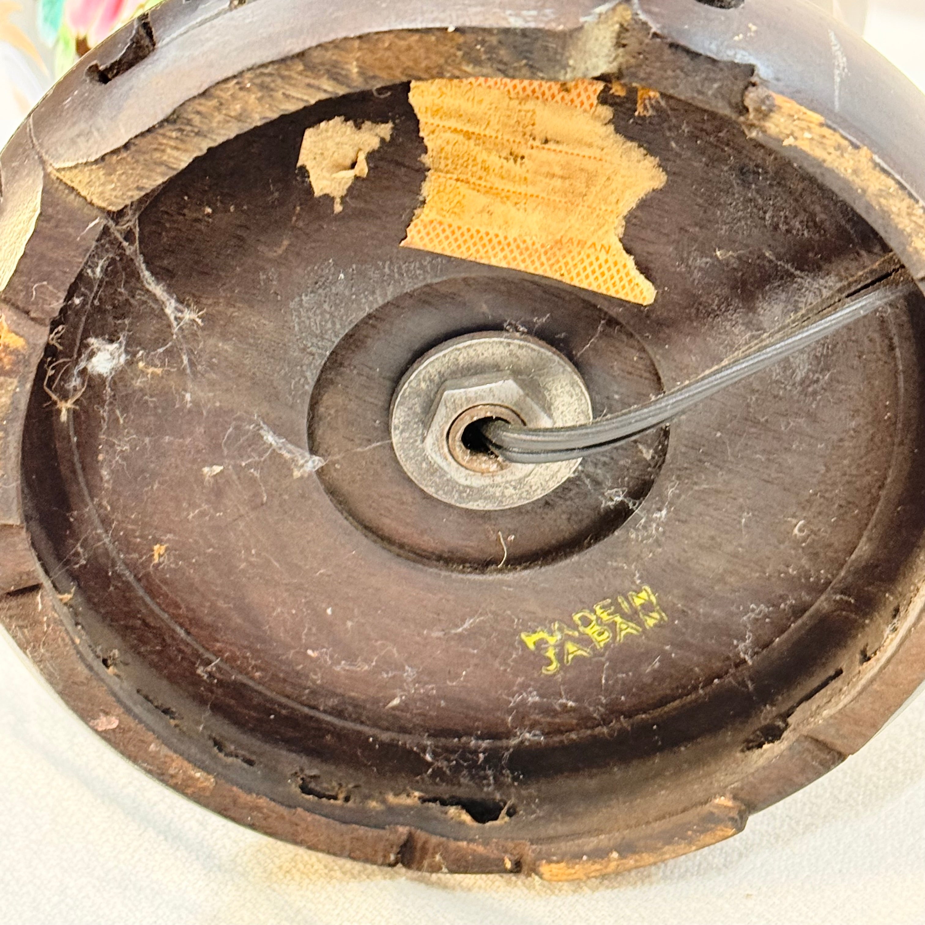 Old and worn-out speaker cone with a wire attached, showing signs of damage and wear.