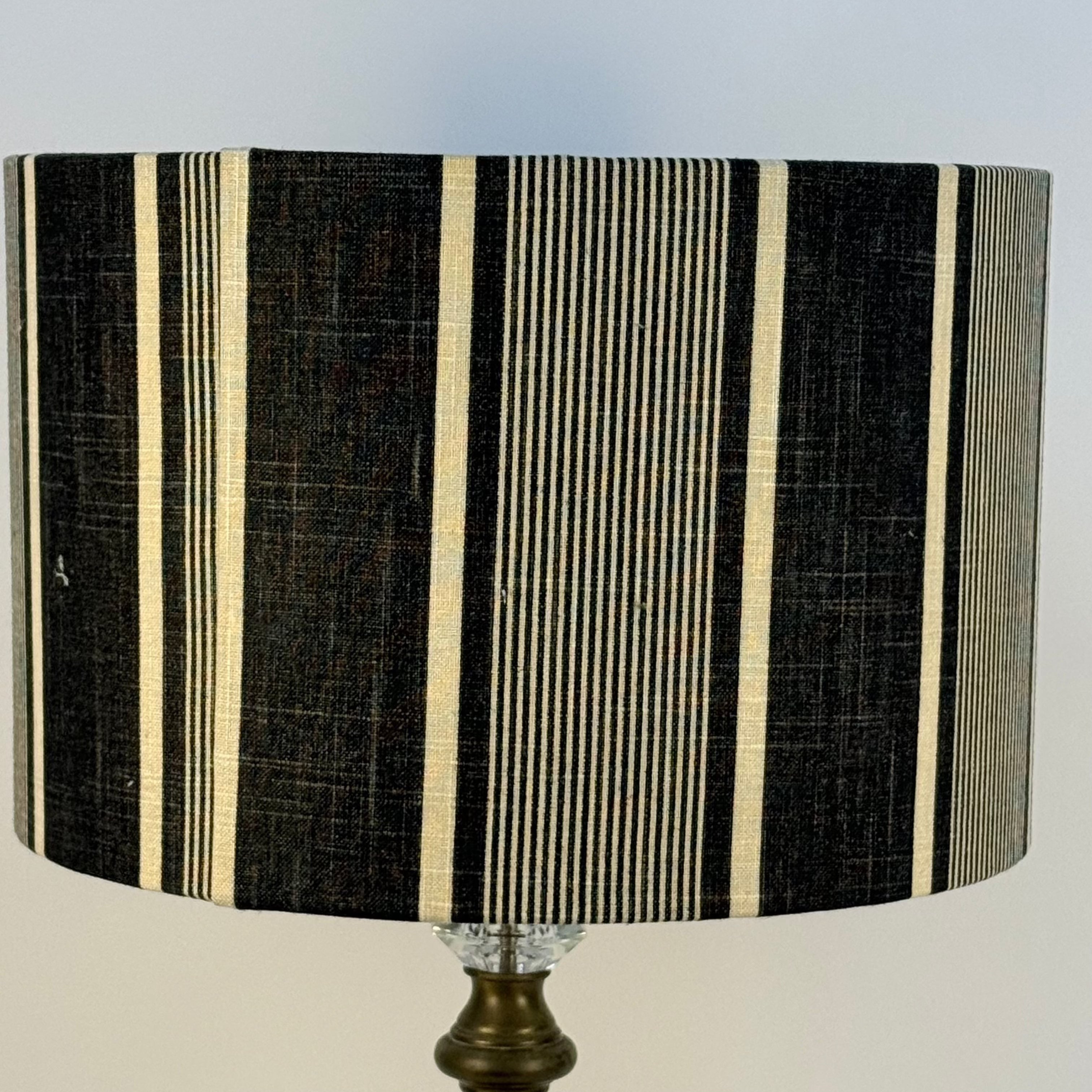 Striped lampshade with black and beige pattern on a plain background