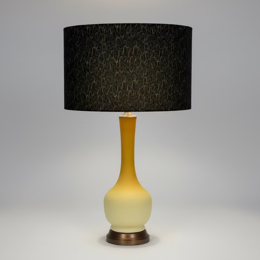Table lamp with a black patterned shade on uranium glass lamp on a wooden surface