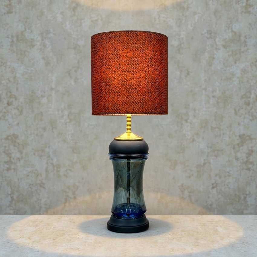 Table lamp with a textured red shade and decorative base on a neutral background