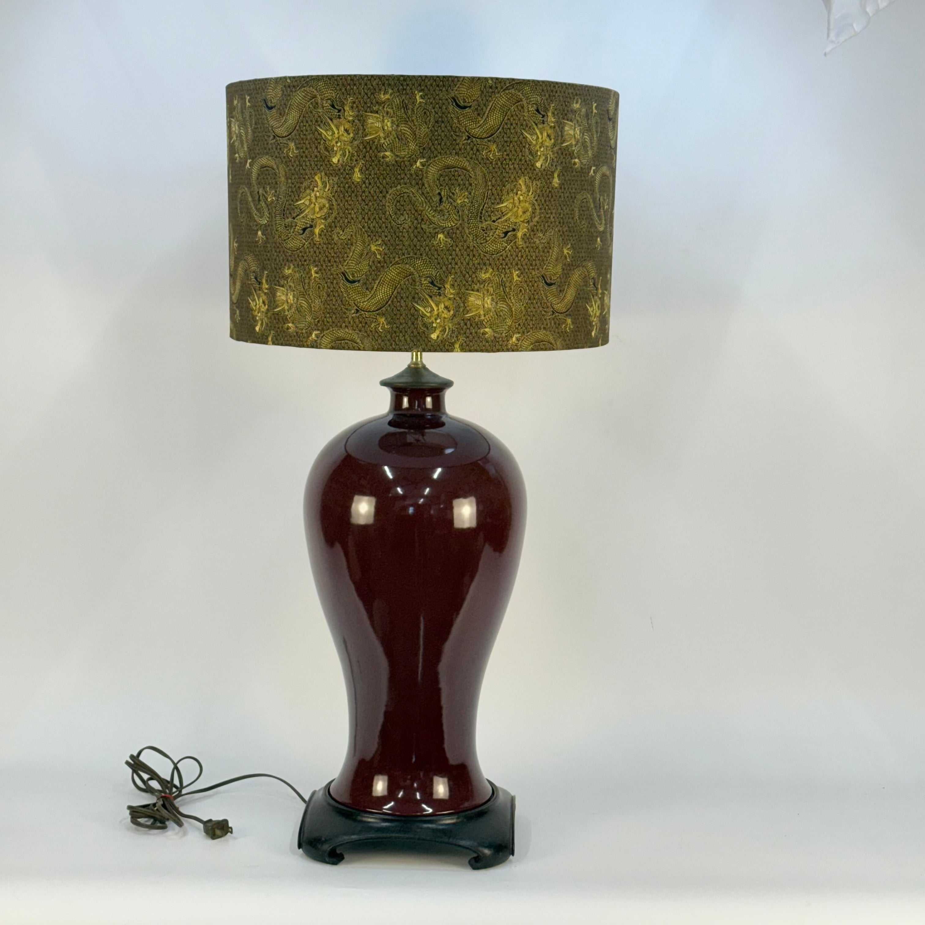 Decorative lamp with a brown base and patterned green shade on a white background