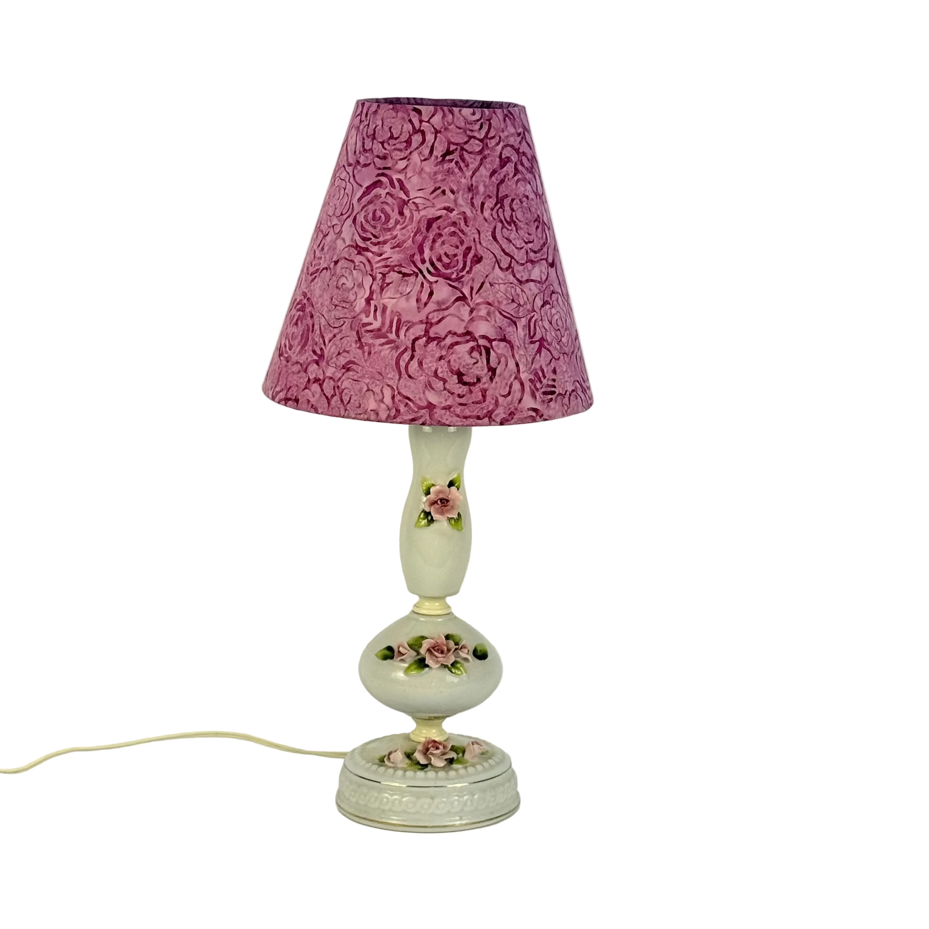 Decorative lamp with a pink floral shade on a white background