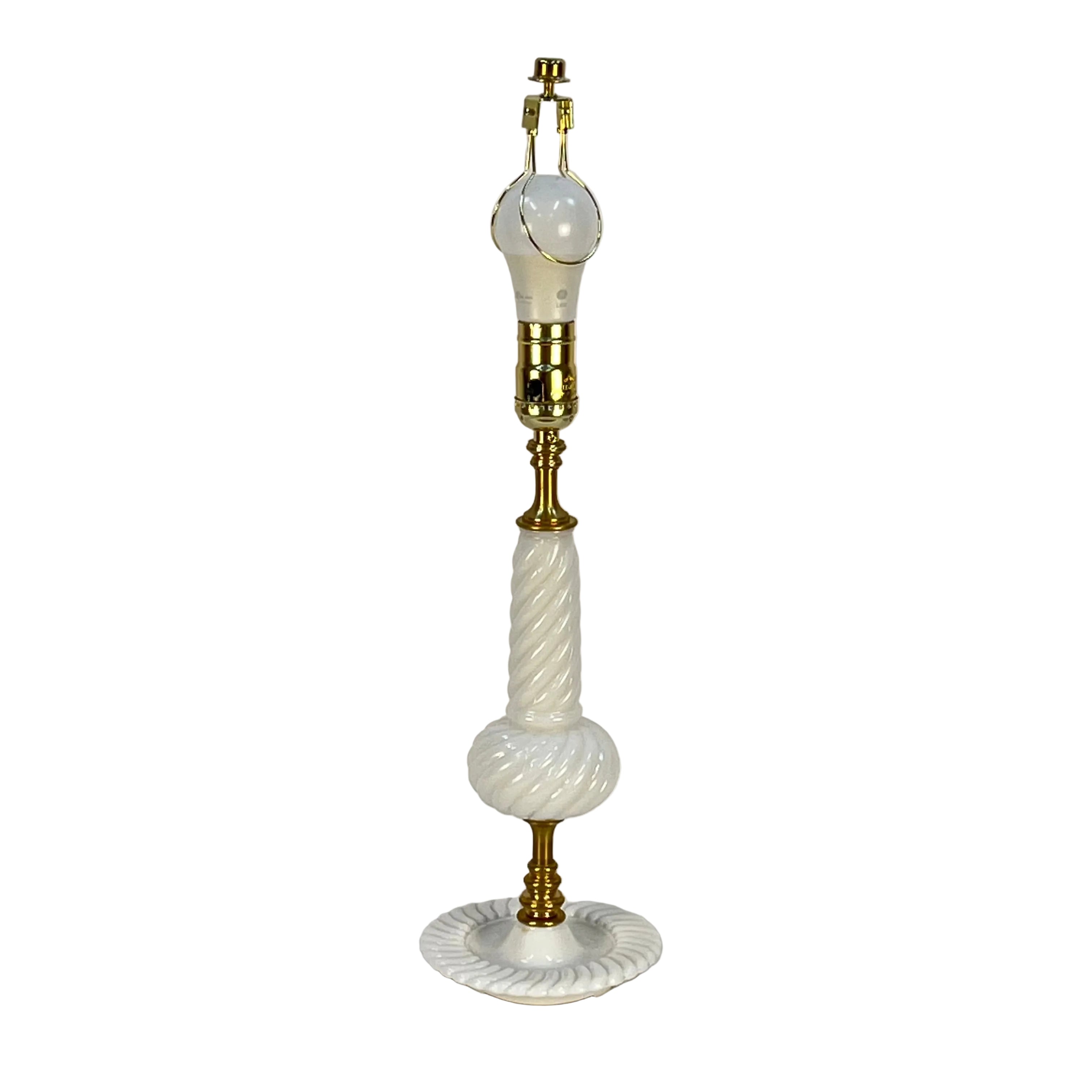 Table lamp with white glass and gold base on a plain background