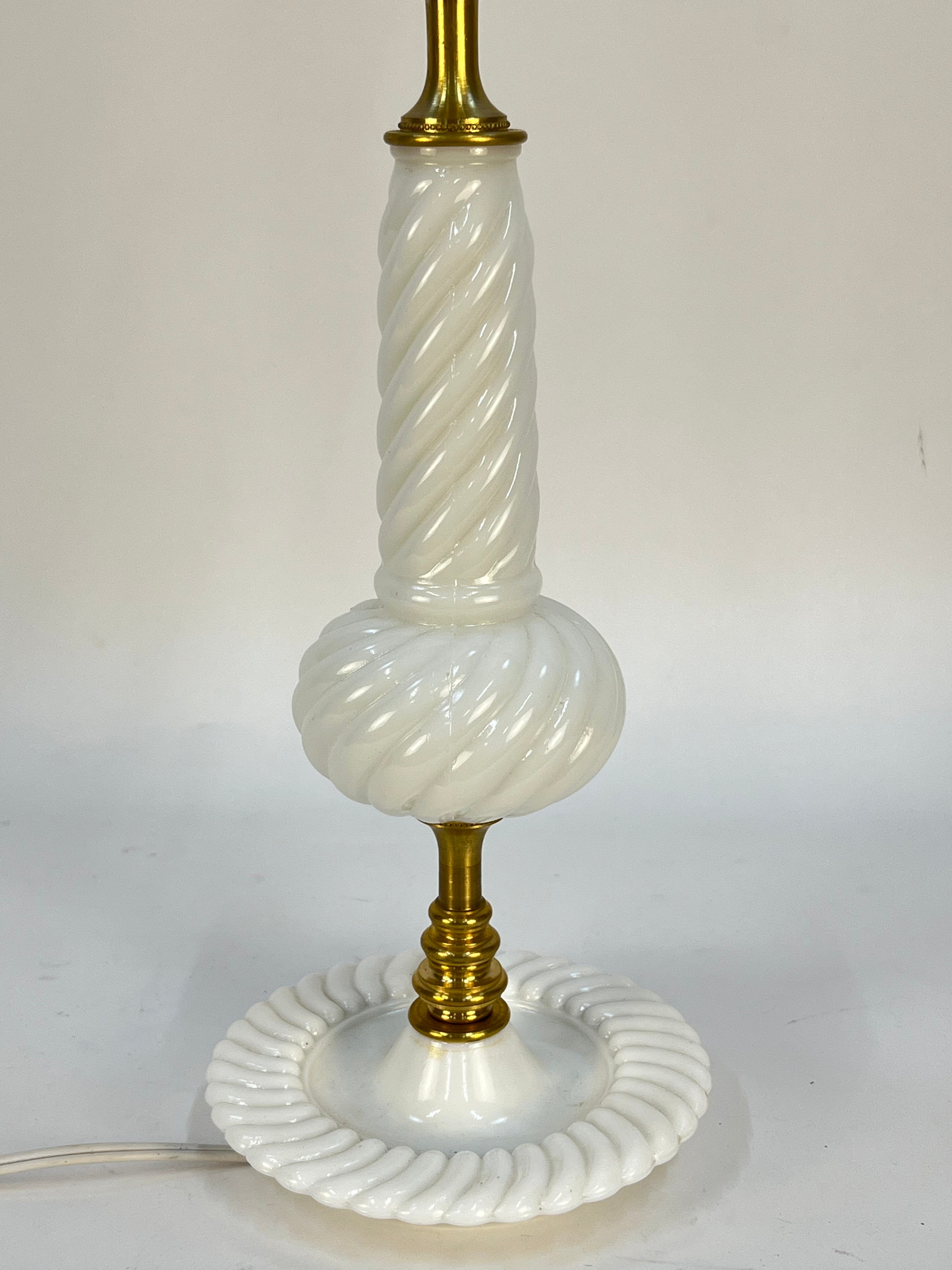 Vintage-style table lamp with white ribbed glass and gold base on a plain background