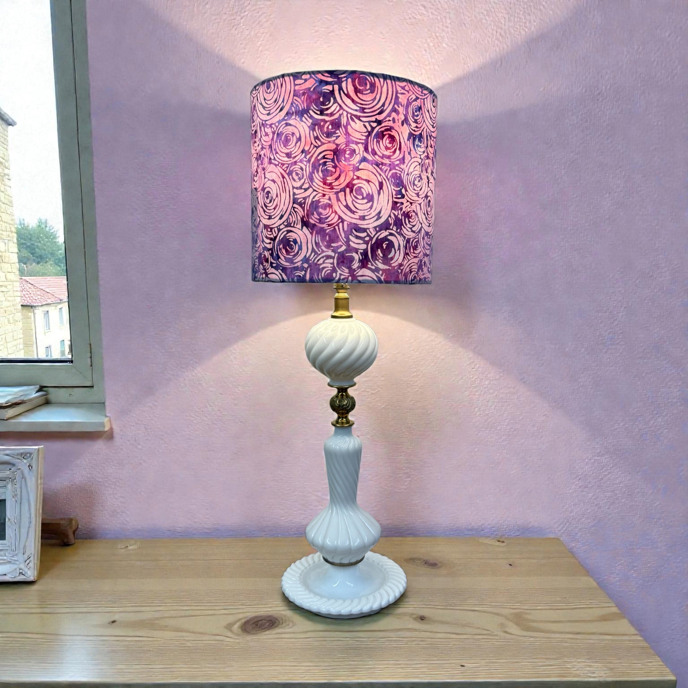 Table lamp with a decorative purple and pink lampshade on a wooden surface.