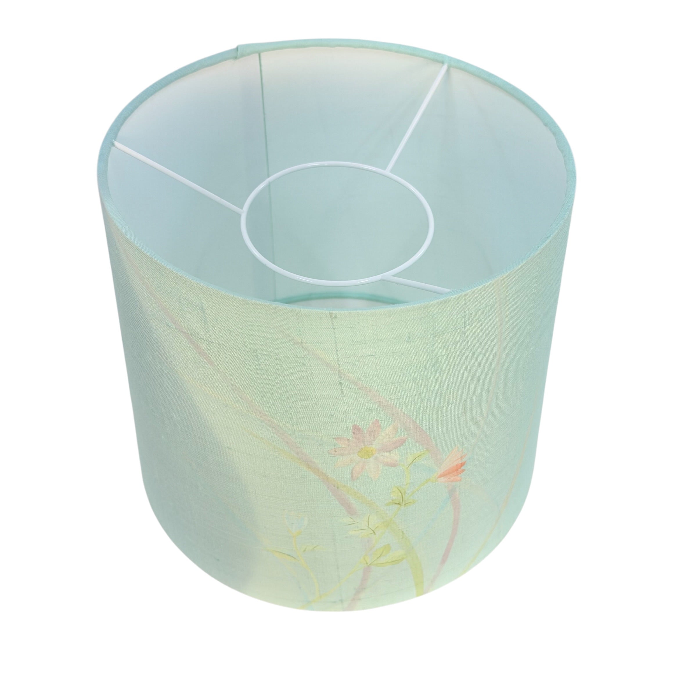 A cylindrical fabric lampshade with a pale mint green base, featuring delicate pink and yellow floral embroidery near the bottom and a white metal support frame visible inside.