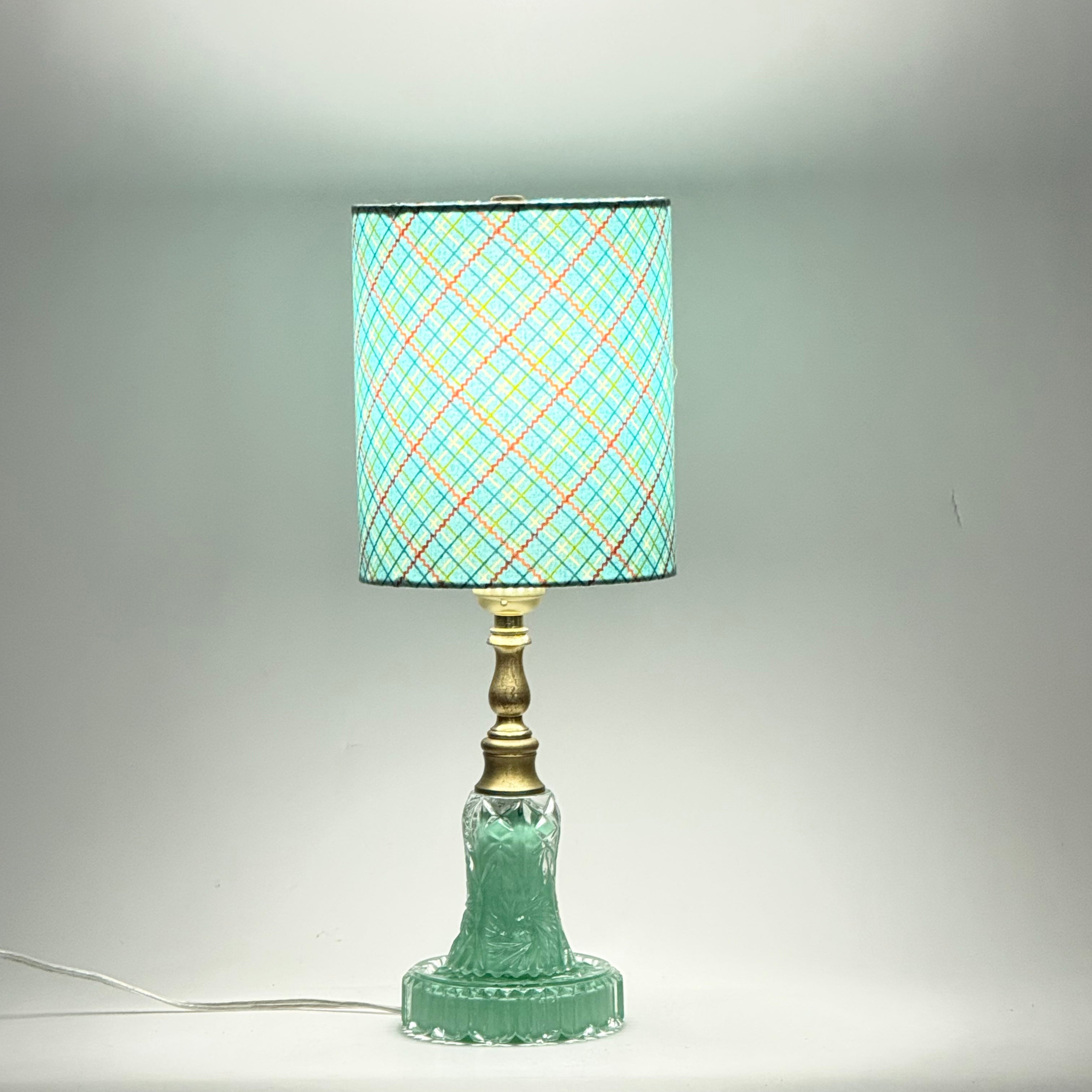 Table lamp with a green base and plaid patterned shade on a gray background