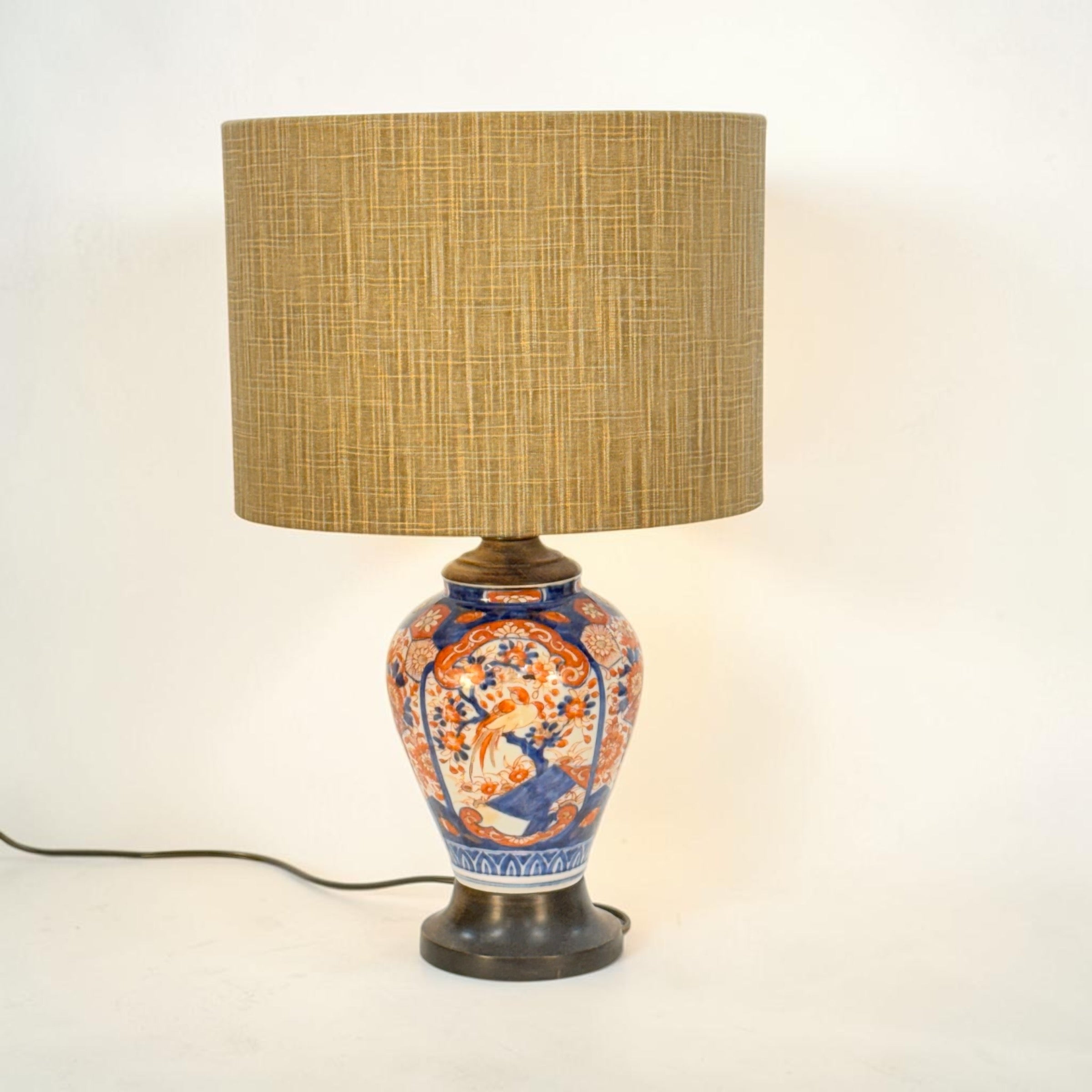 Decorative table lamp with a ceramic base and wicker shade on a white background
