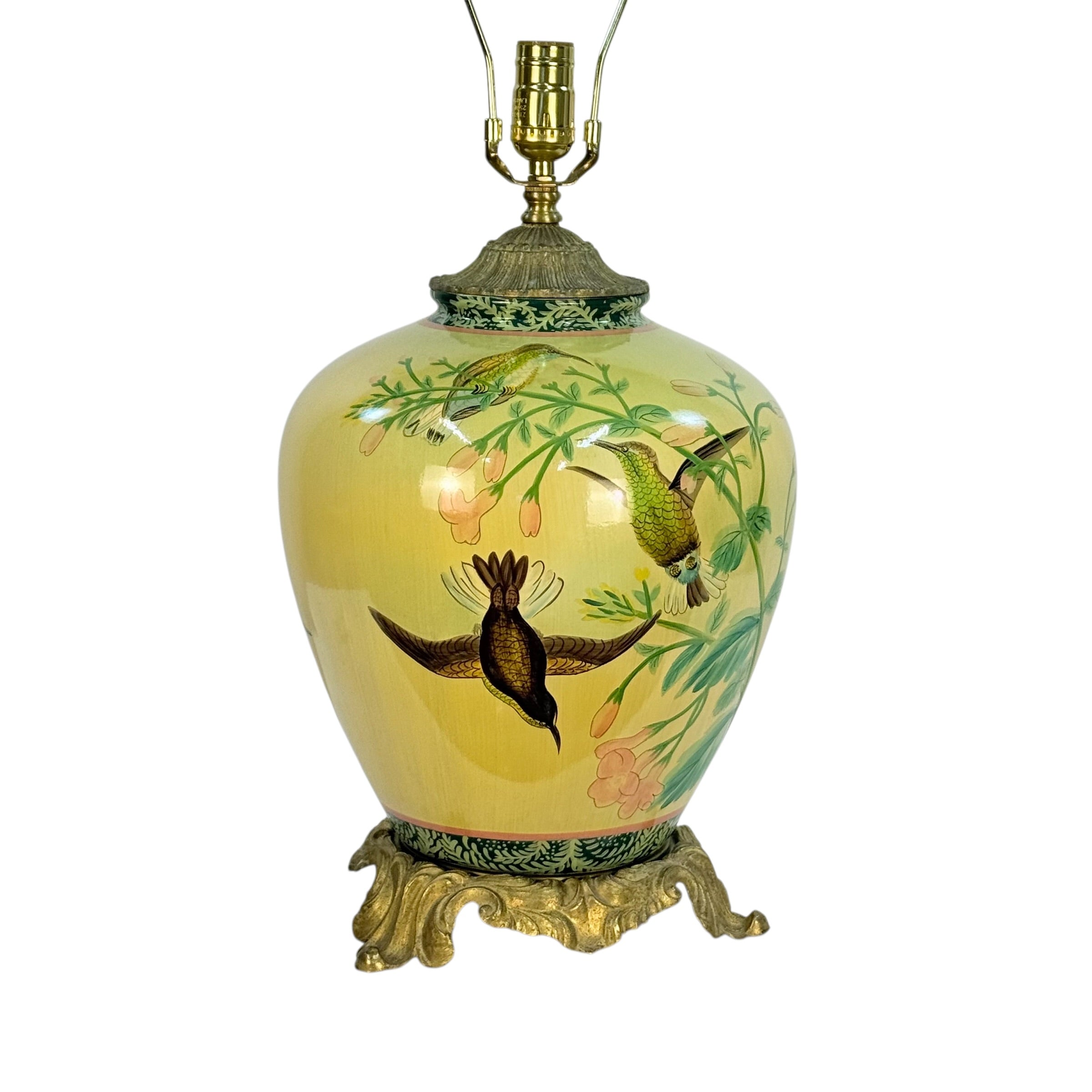 A vintage-style ceramic table lamp with a glossy pale yellow-green vase-shaped body decorated with hand-painted birds and floral motifs, topped with a gold-toned metal lamp fixture and ornate base.