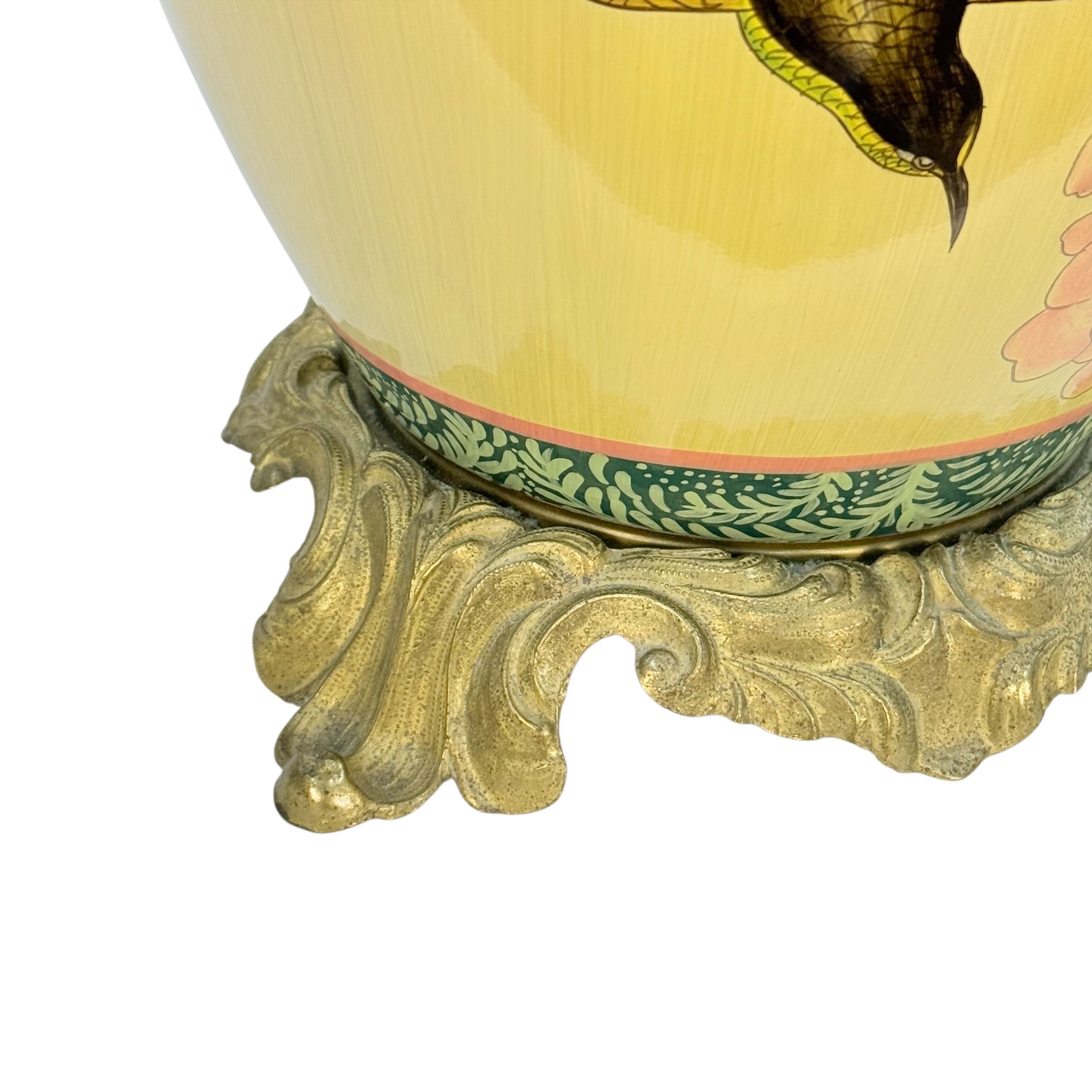 Close-up of a decorative ceramic vase base with a pale yellow body, painted floral motif, green patterned band, and ornate gold-colored pedestal foot on a white background.