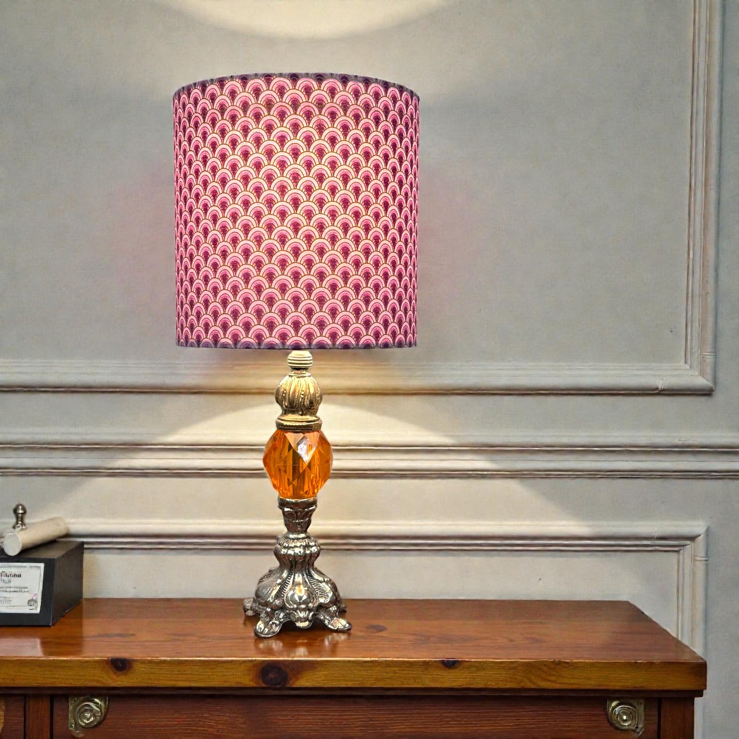 Decorative table lamp with a pink patterned shade on a wooden surface.