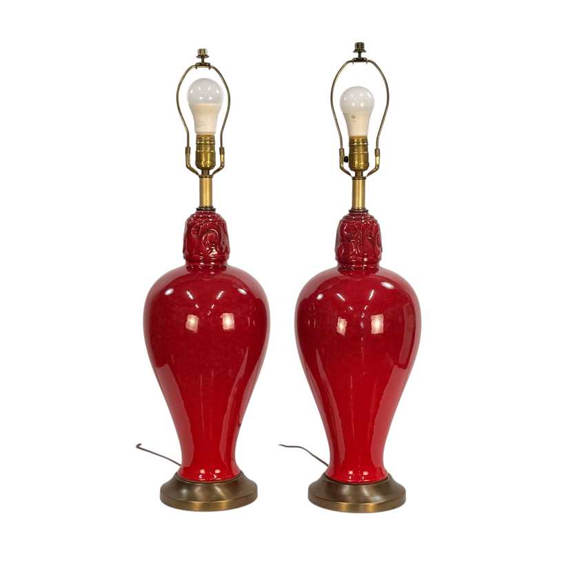 A pair of vintage-style table lamps with glossy red ceramic vase-shaped bases and brass metal necks, bases, and wire shades, shown against a plain white background.
