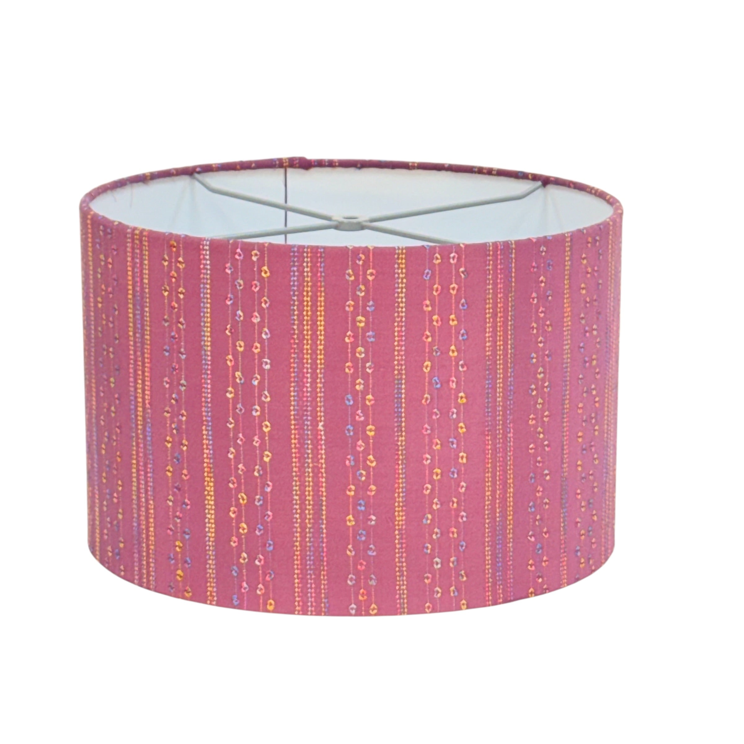 A cylindrical fabric lampshade with a pink base color, decorated with vertical dotted stripes in yellow, orange, and blue, on a plain white background.