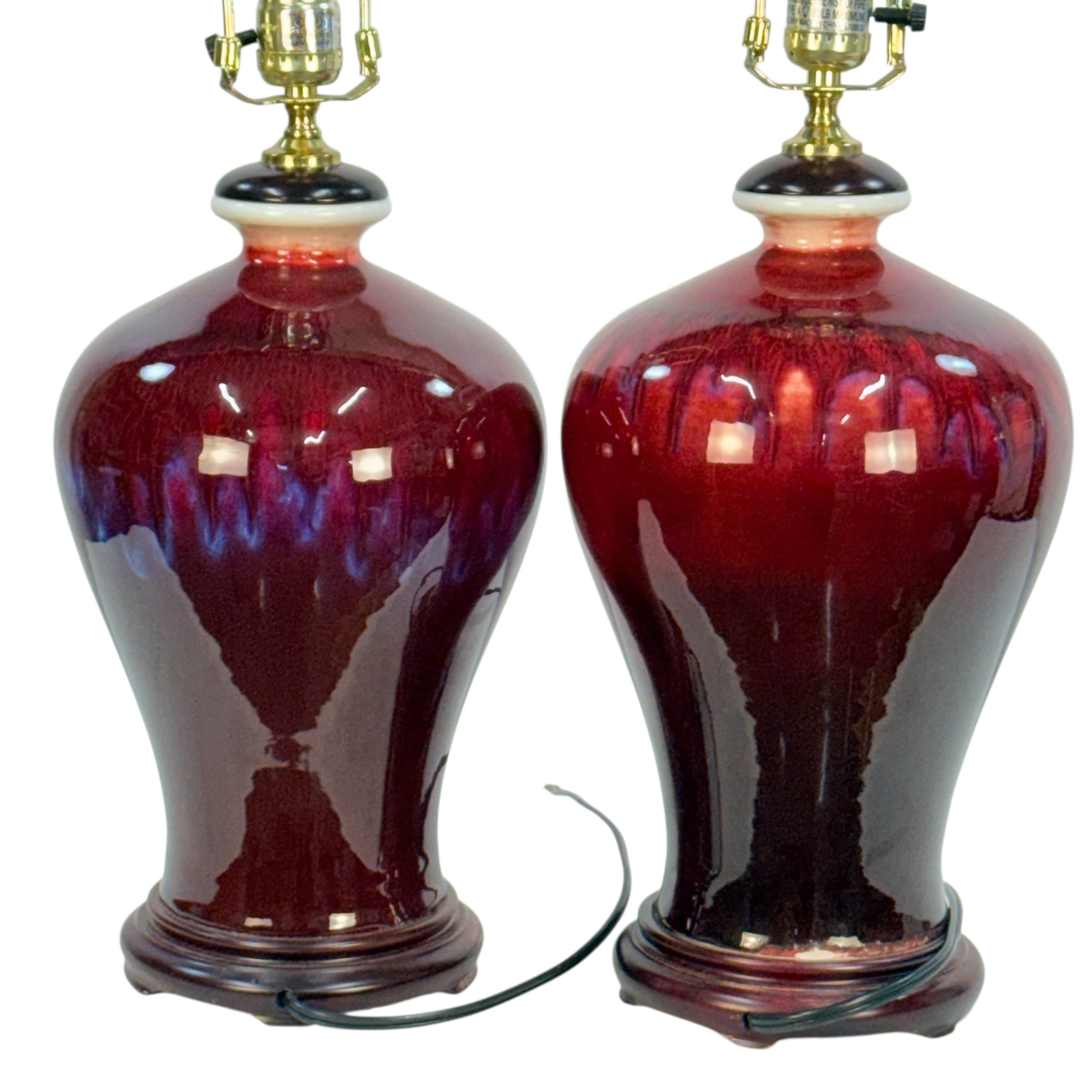 Two matching glossy ceramic table lamps with deep burgundy and purple iridescent glaze, gold metal lamp bases, and dark wooden bases, shown on a white background.