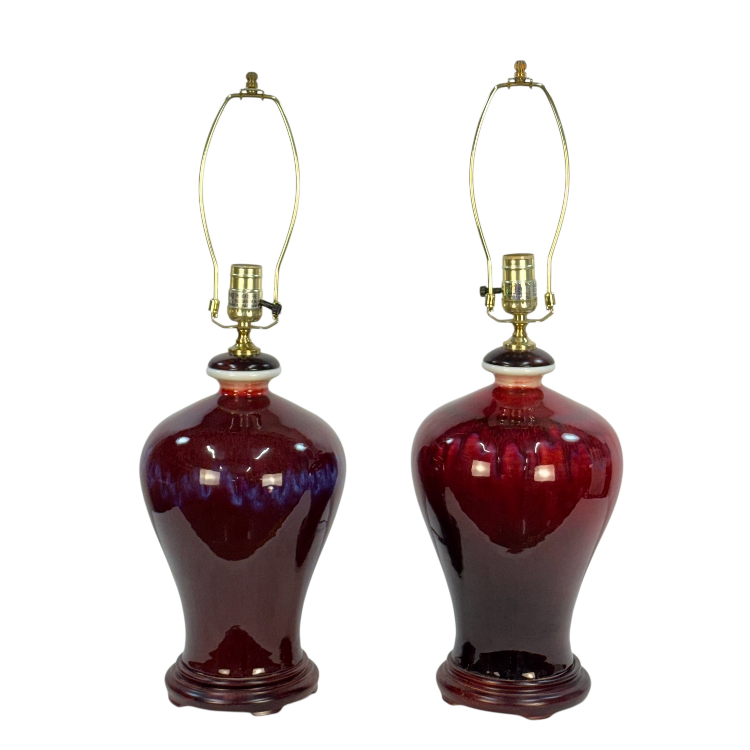 A pair of vintage-style table lamps with glossy deep red ceramic vase-shaped bases and brass-colored arched lampshades, shown against a plain white background.
