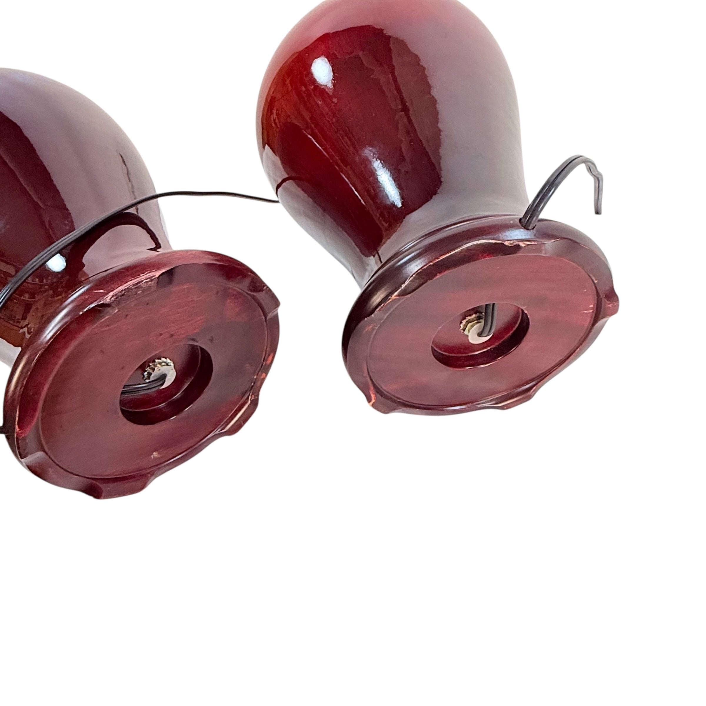 Two glossy dark red glass or resin decorative vases with metal wire hangers, shown against a plain white background.