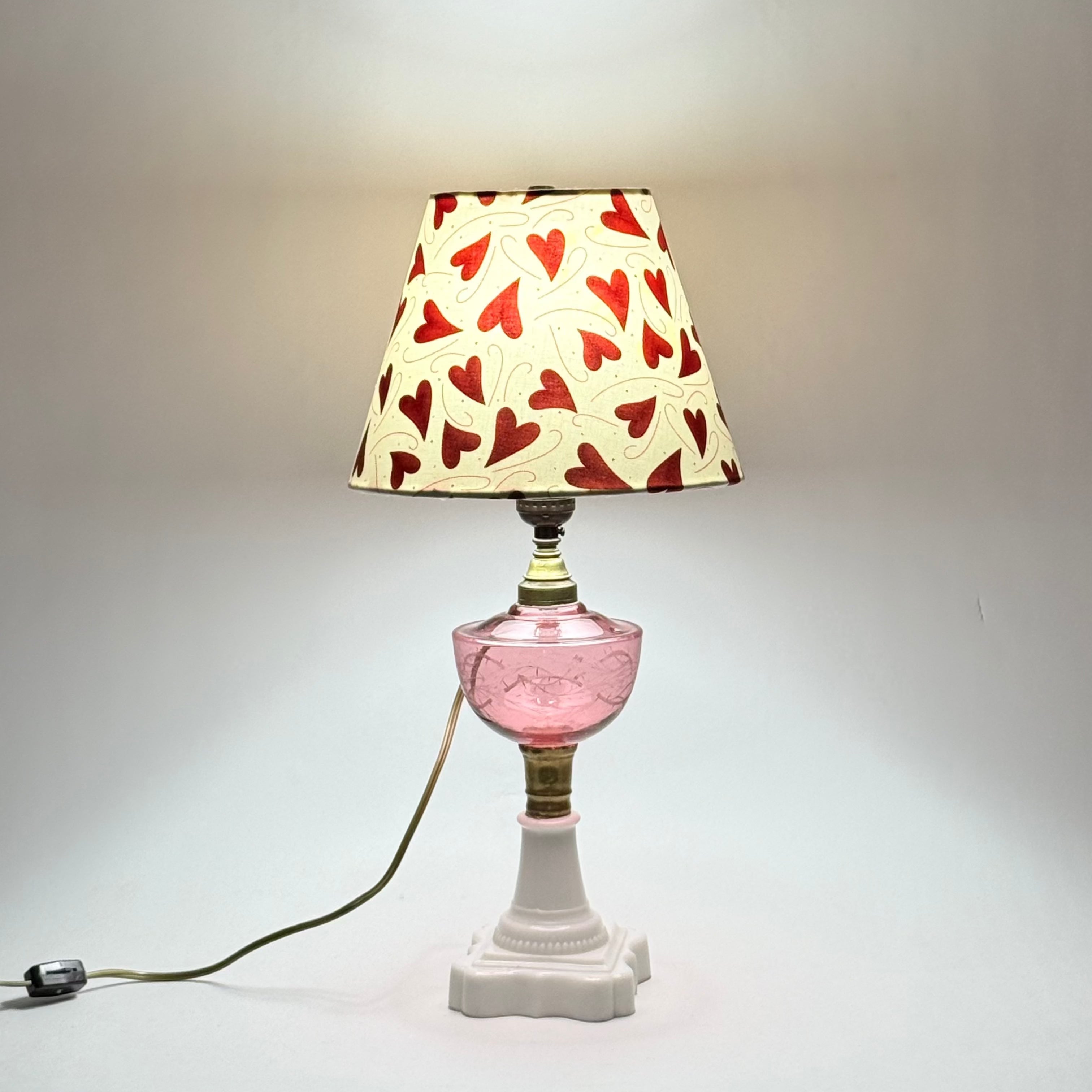 Lamp with a heart-patterned shade on a plain background