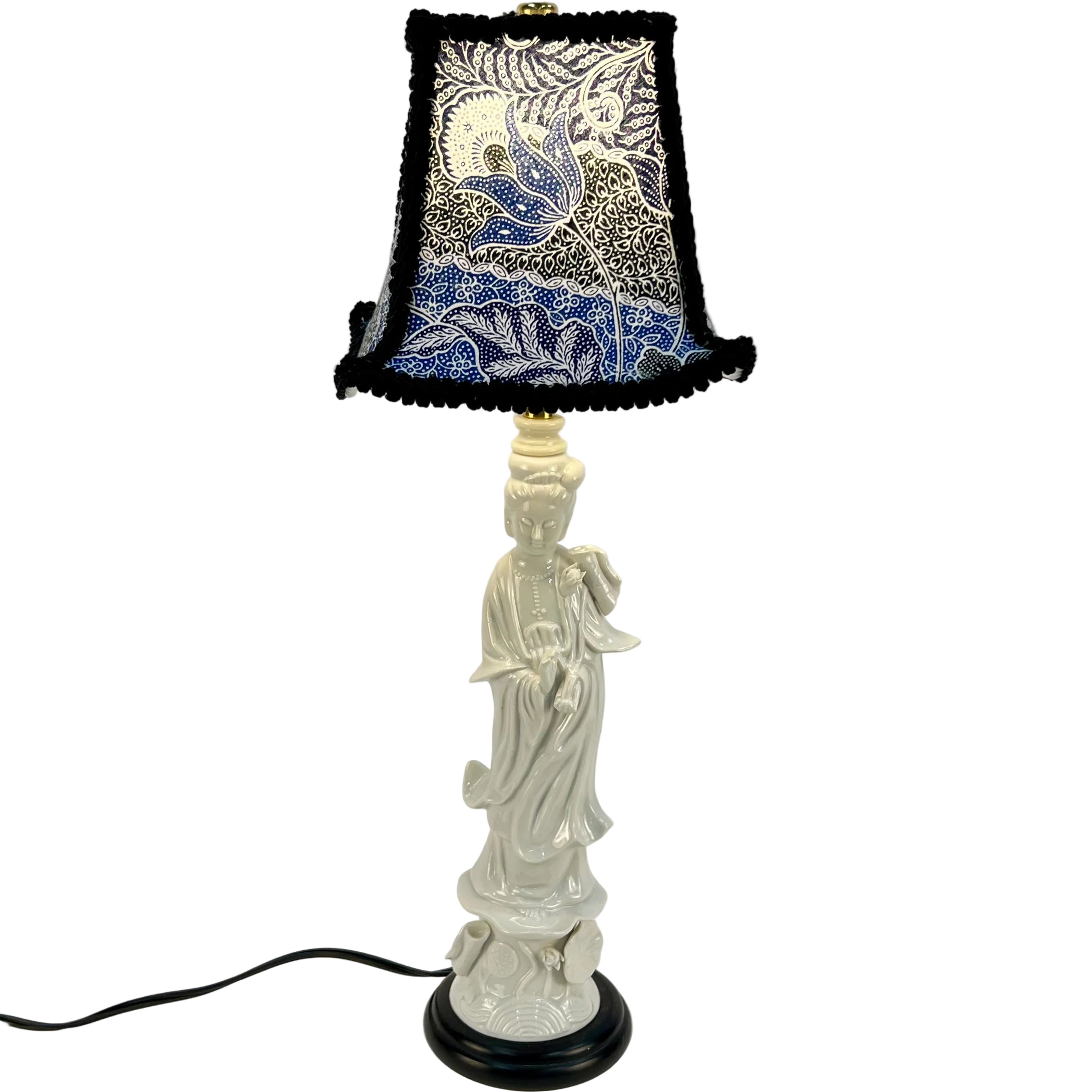 Decorative lamp with a figurine base and patterned lampshade on a white background