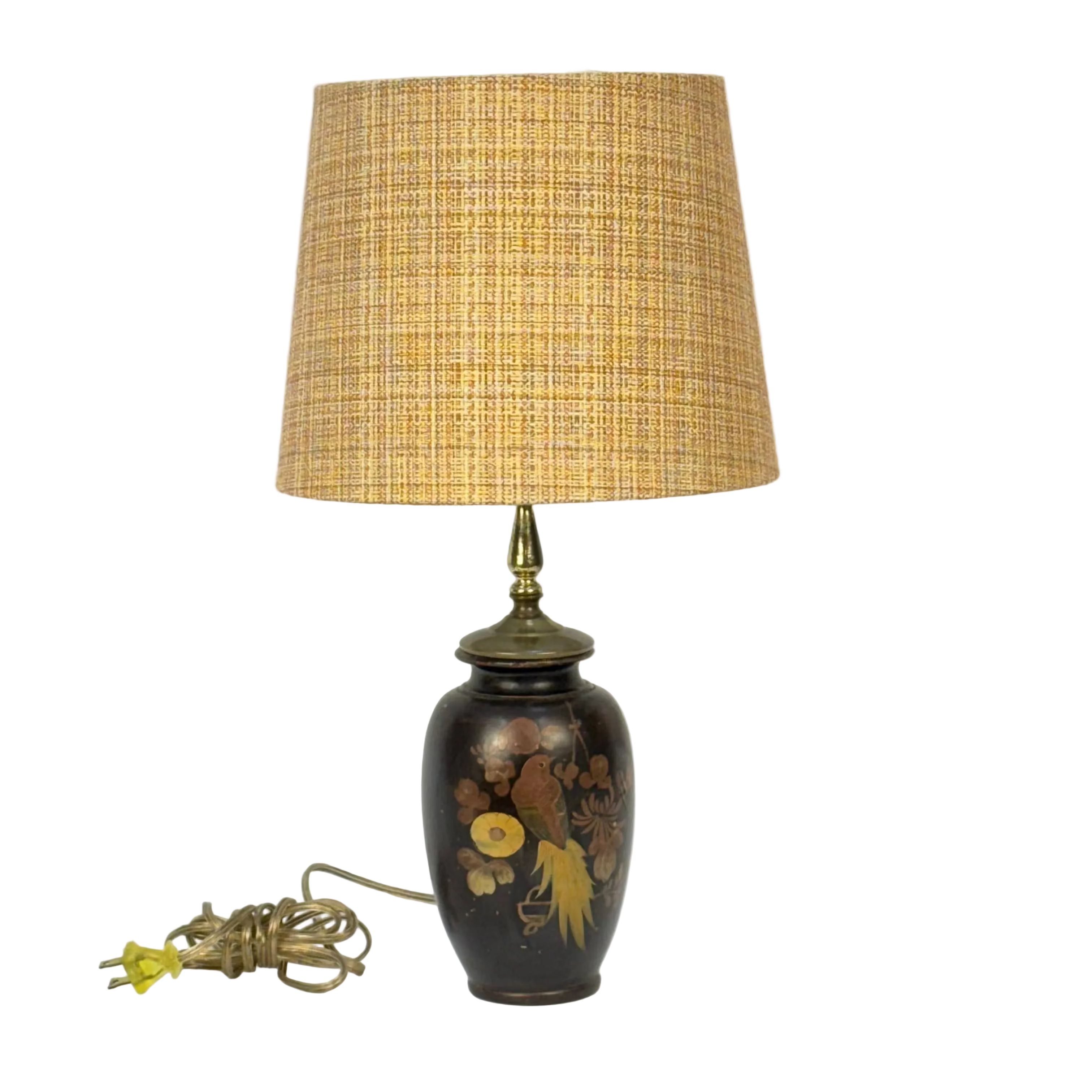 A vintage-style table lamp with a textured beige woven shade, a dark brown ceramic base decorated with gold and yellow floral motifs, and a brass-toned neck. The coiled power cord with a yellow plug is placed to the left on a plain white background.