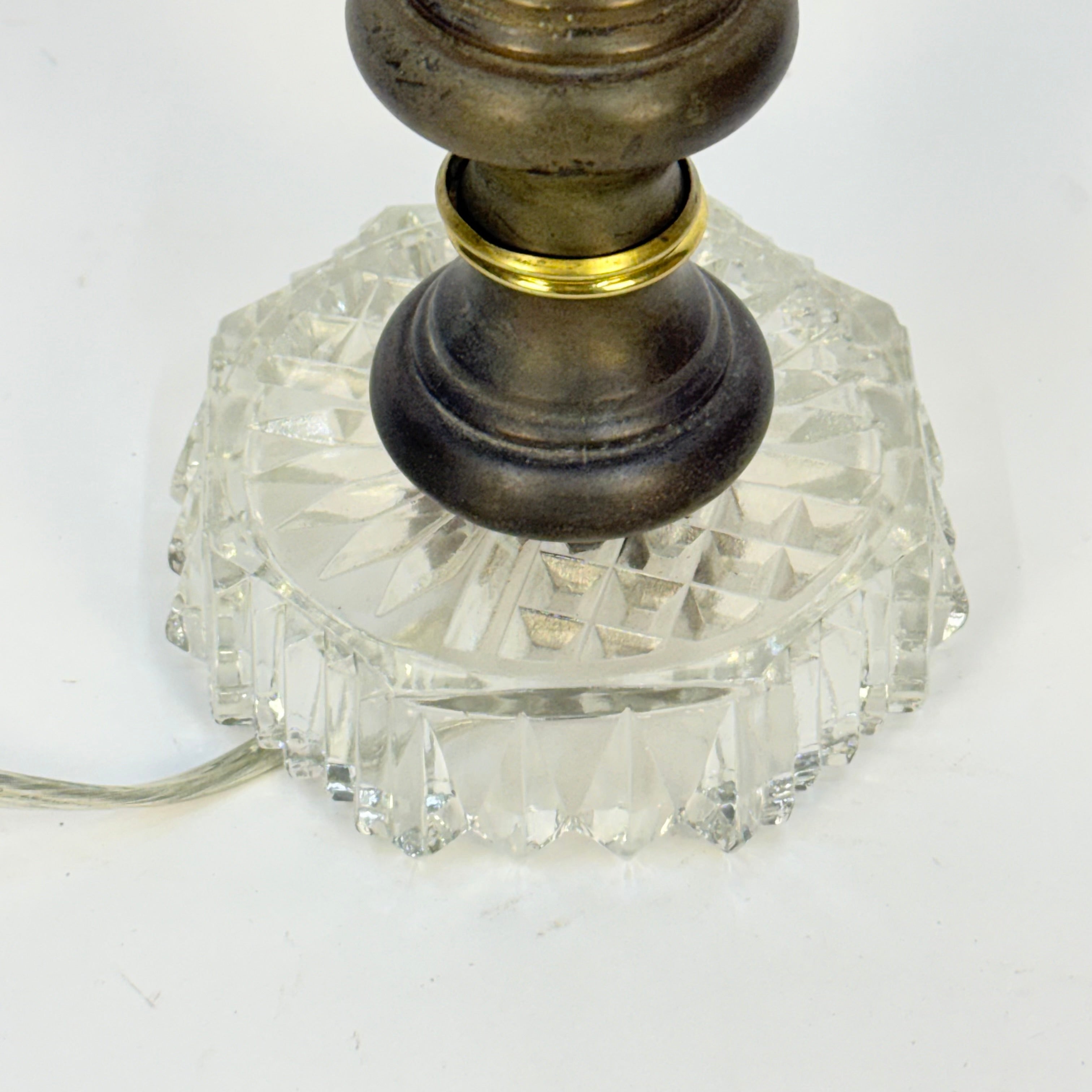 Close-up of a lamp with a crystal base and bronze fitting on a white background