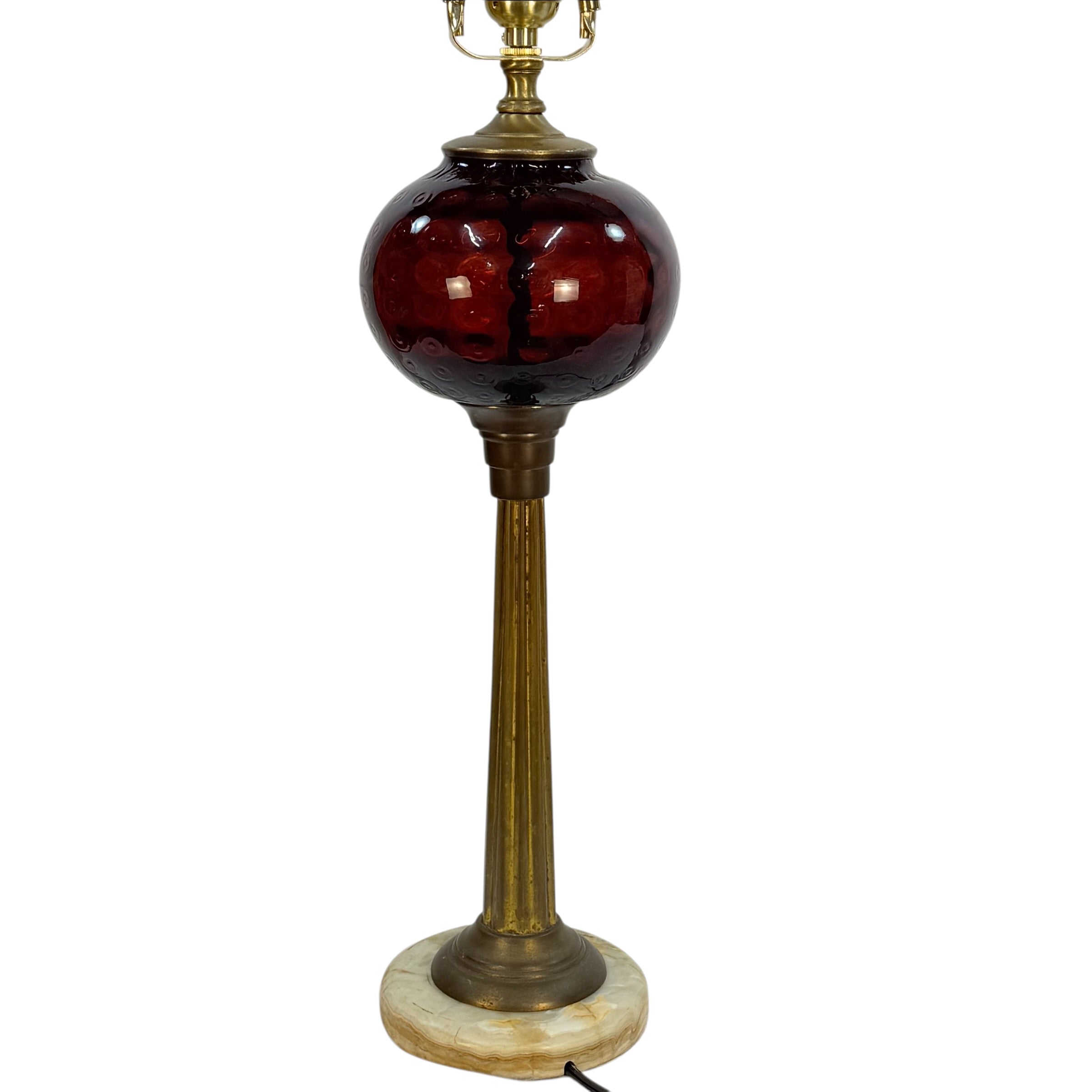 A vintage-style table lamp featuring a dark red glass globe shade, a fluted brass stem, and a round white marble base on a white background.
