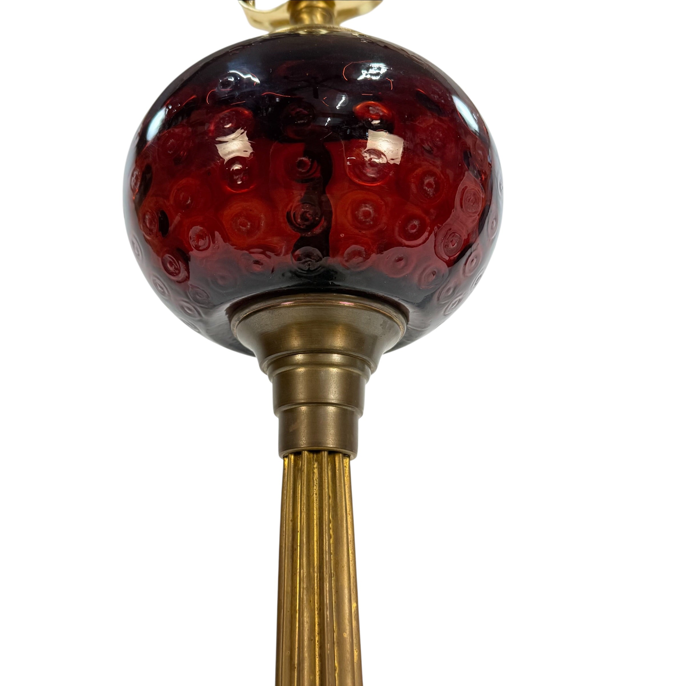 Close-up of a decorative chandelier or pendant light fixture showing a glossy dark red glass globe with a bubble pattern, a brass-toned metal collar, and a fluted gold-toned stem against a white background.