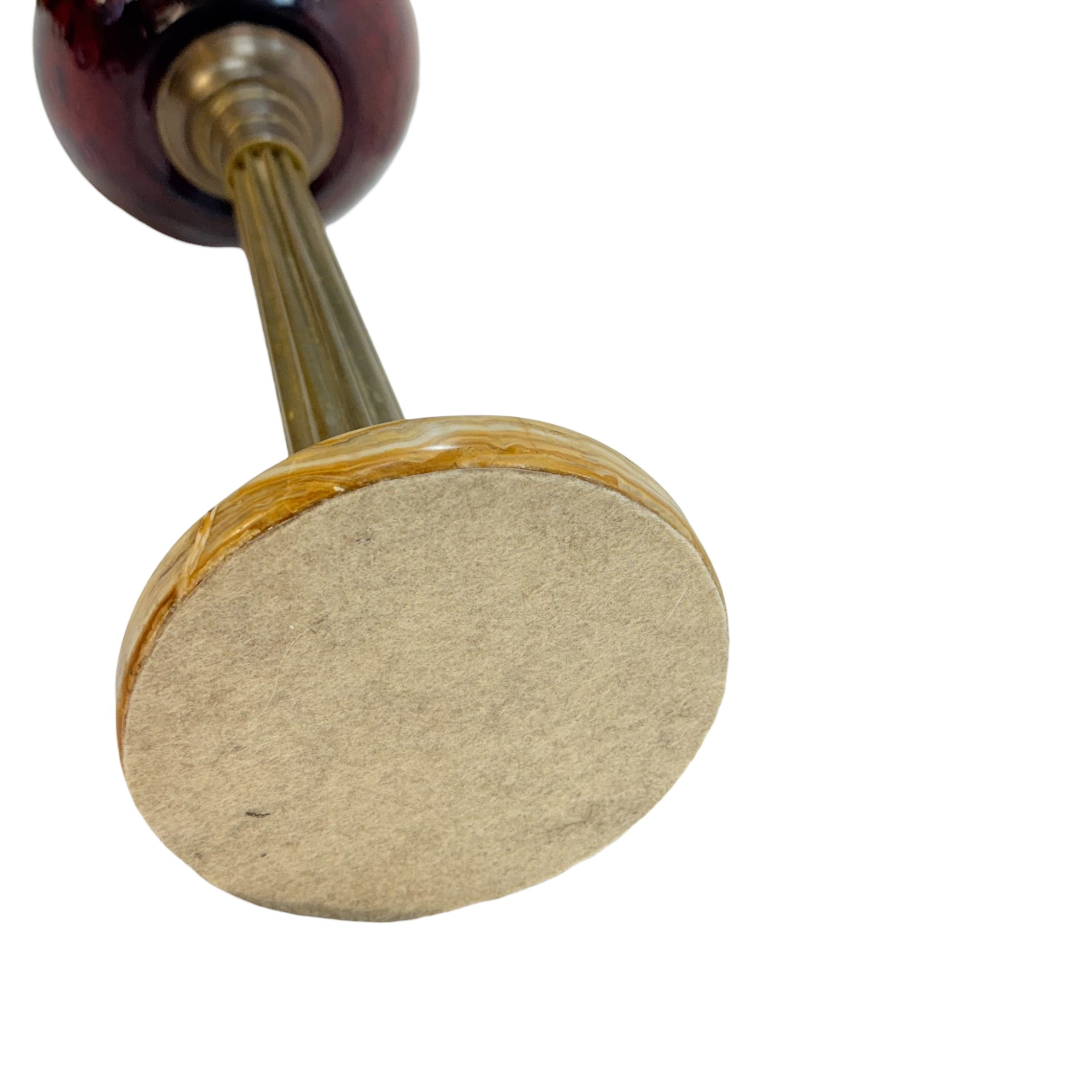 Close-up of a stamping or mallet tool with a round beige felt pad, a brass-toned metal stem, and a dark reddish-brown wooden top on a white background.