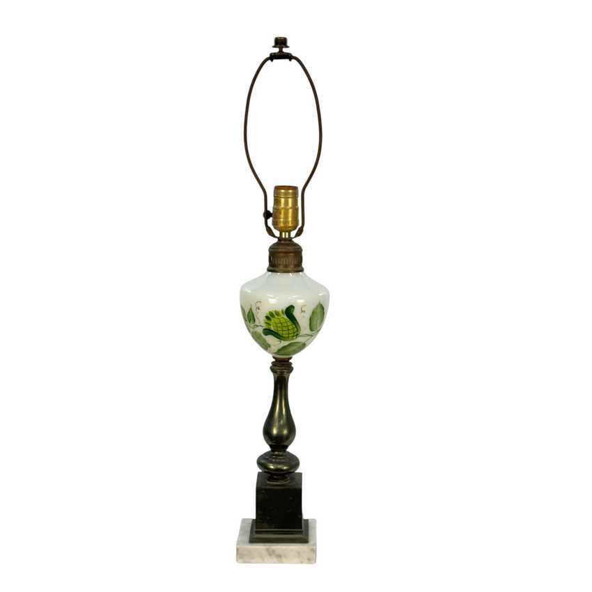 A vintage-style table lamp featuring a white milk glass bulb decorated with green leaf patterns, mounted on a dark bronze-toned metal base with a square marble base.