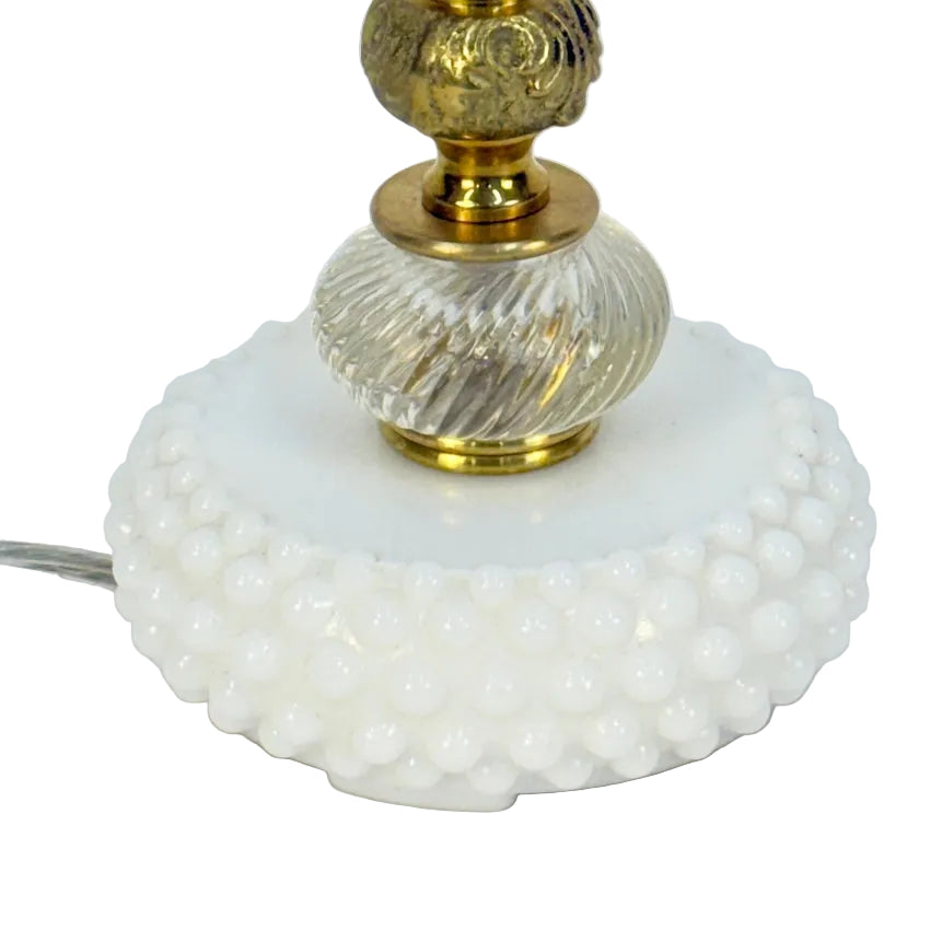 Decorative lamp with gold fixture and white textured base on a light gray background
