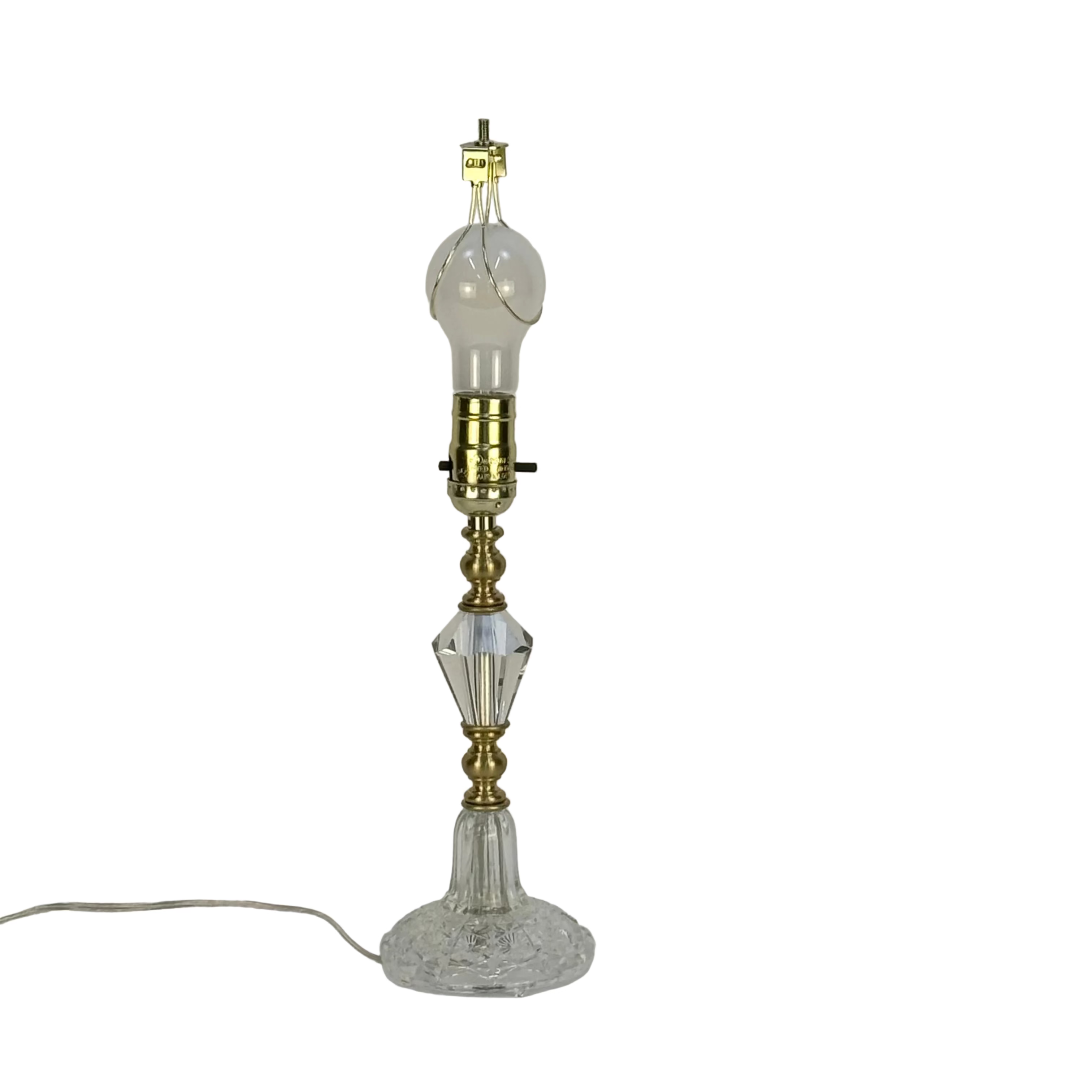 Vintage-style lamp with glass base and brass fitting on a plain background