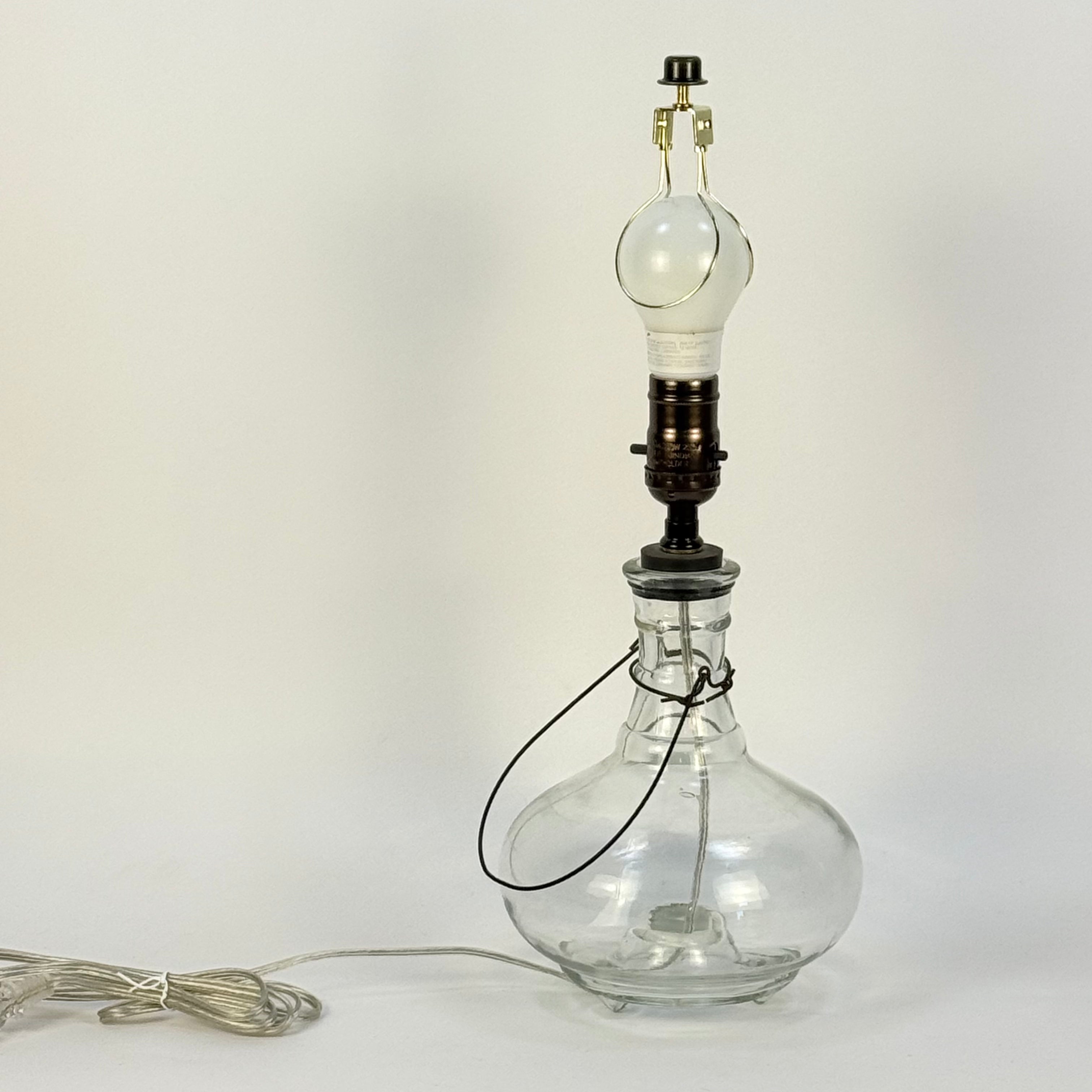 Clear glass bottle repurposed as a lamp with a light bulb on a white background