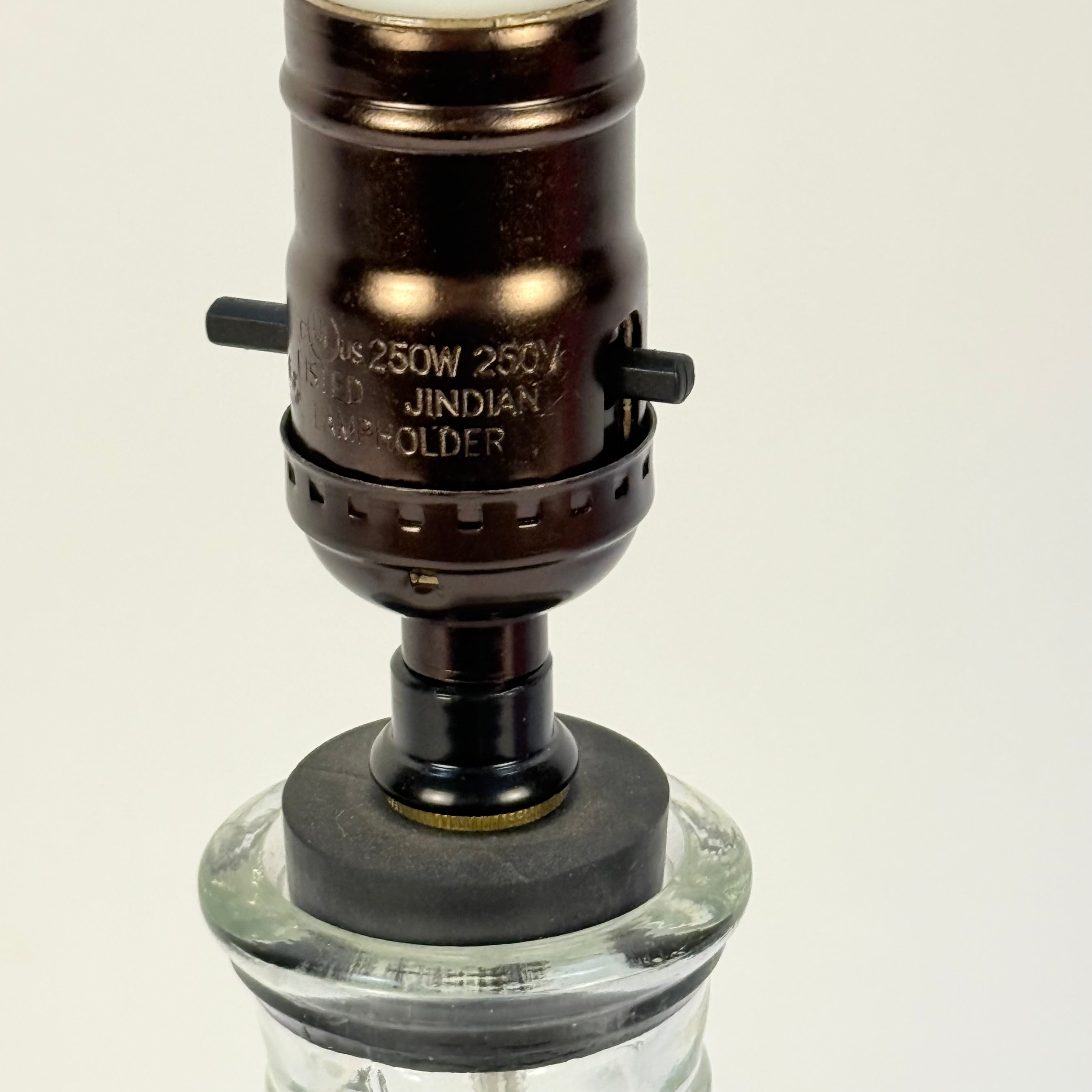 Vintage-style lamp with glass base and metal fitting on a beige background