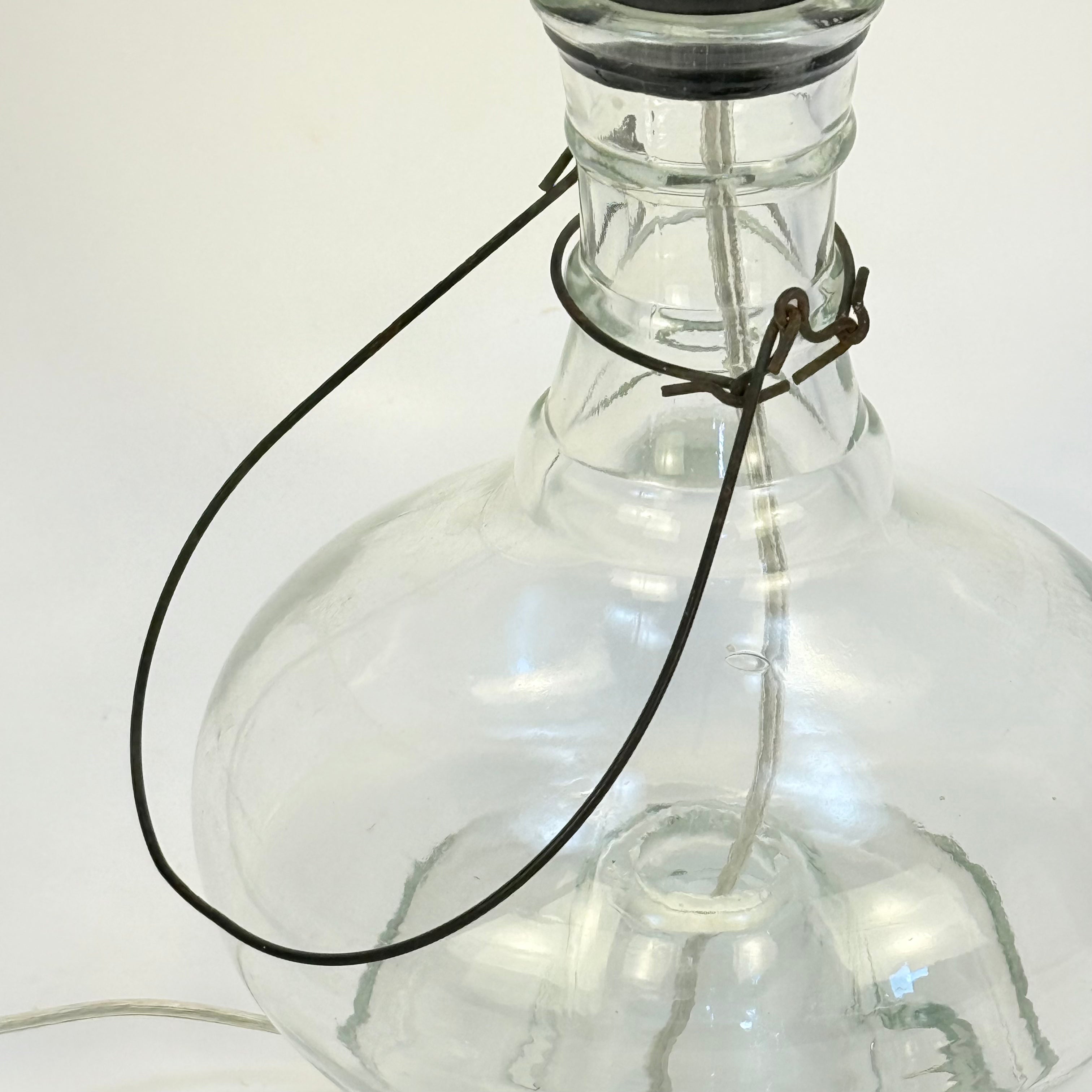 Clear glass bottle with a black wire attached on a white background