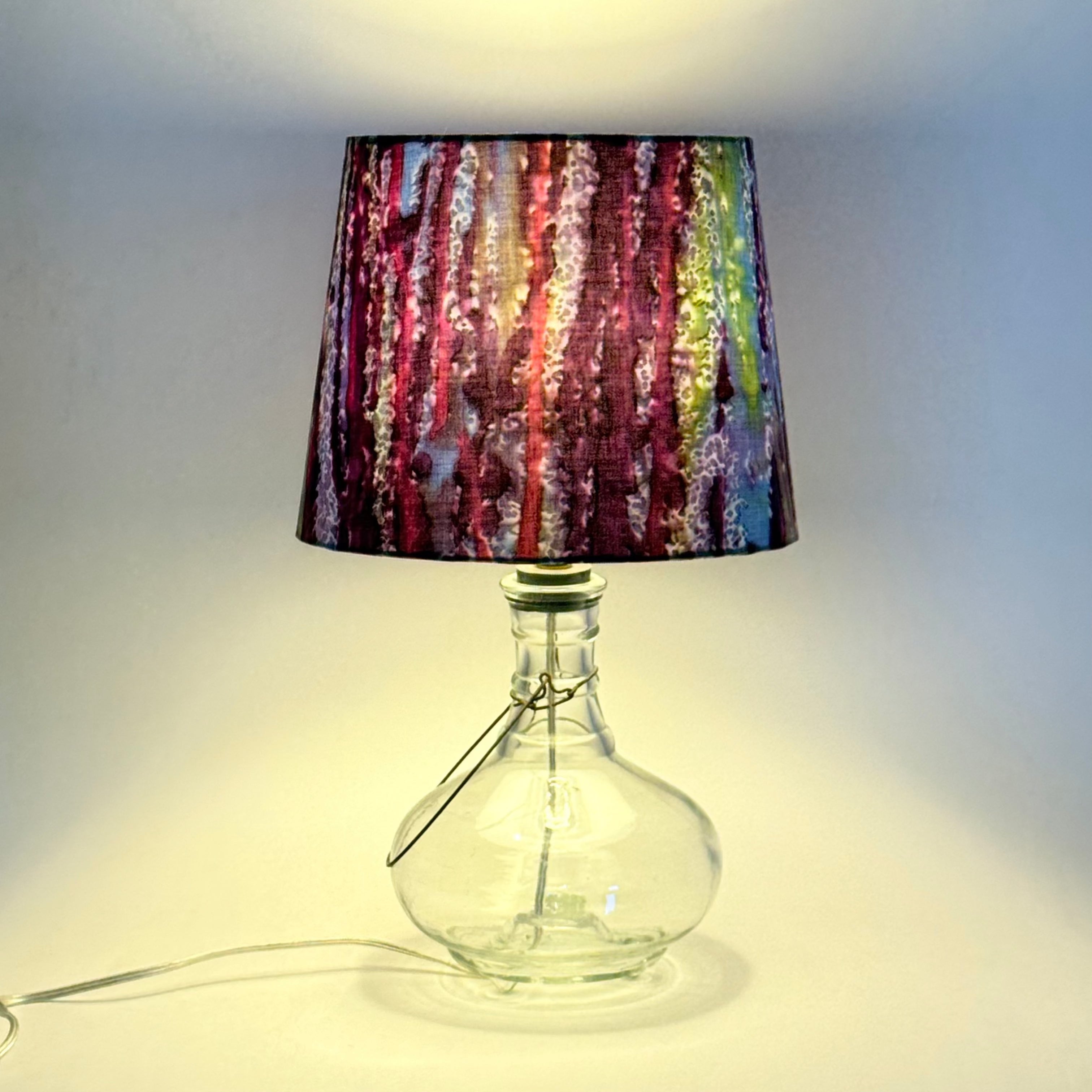 Lamp with a colorful shade and clear glass base on a white background