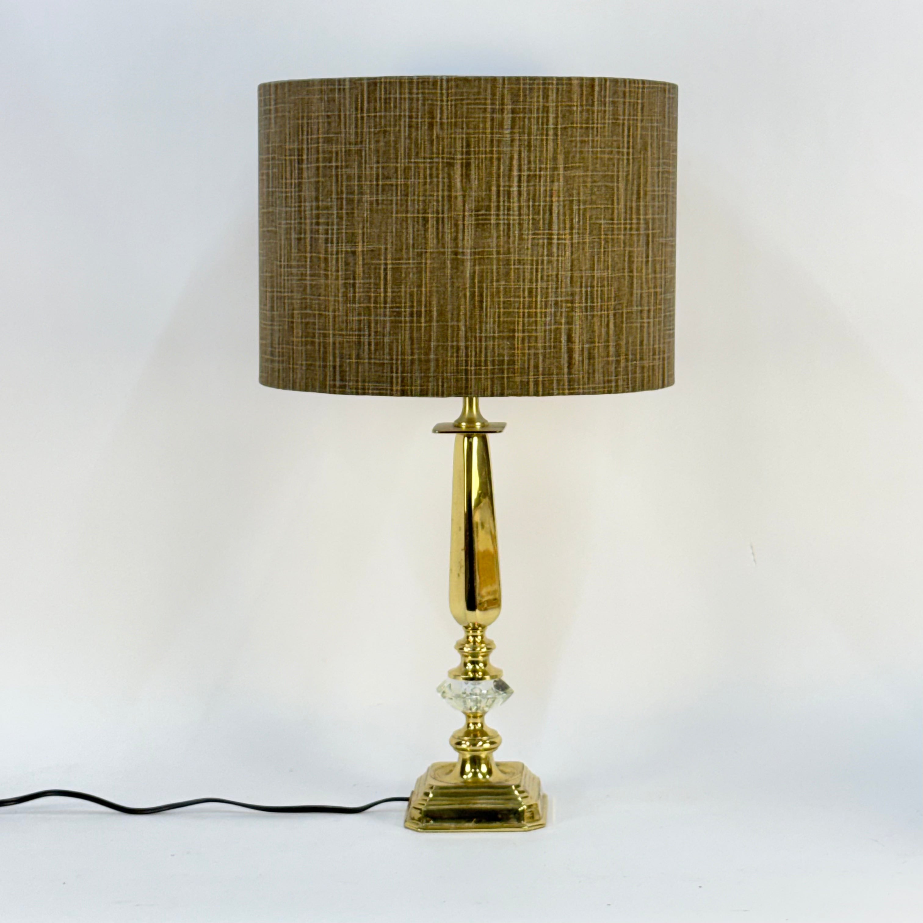 Table lamp with gold base and brown fabric shade on a white background