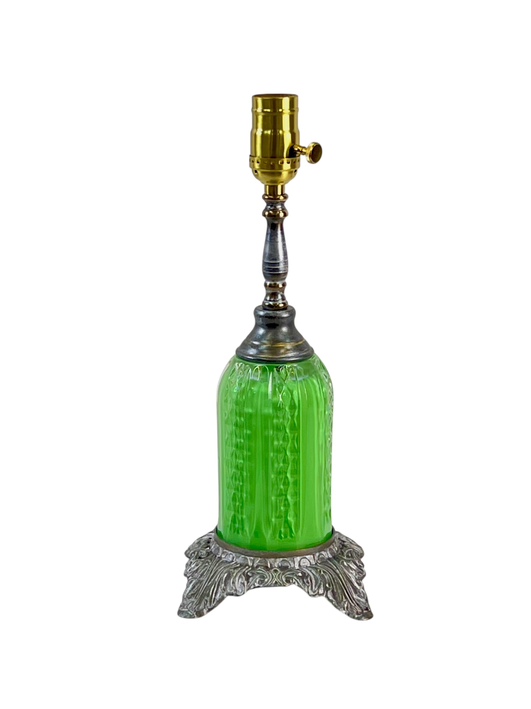 Green glass lamp with silver base and gold accent on a white background