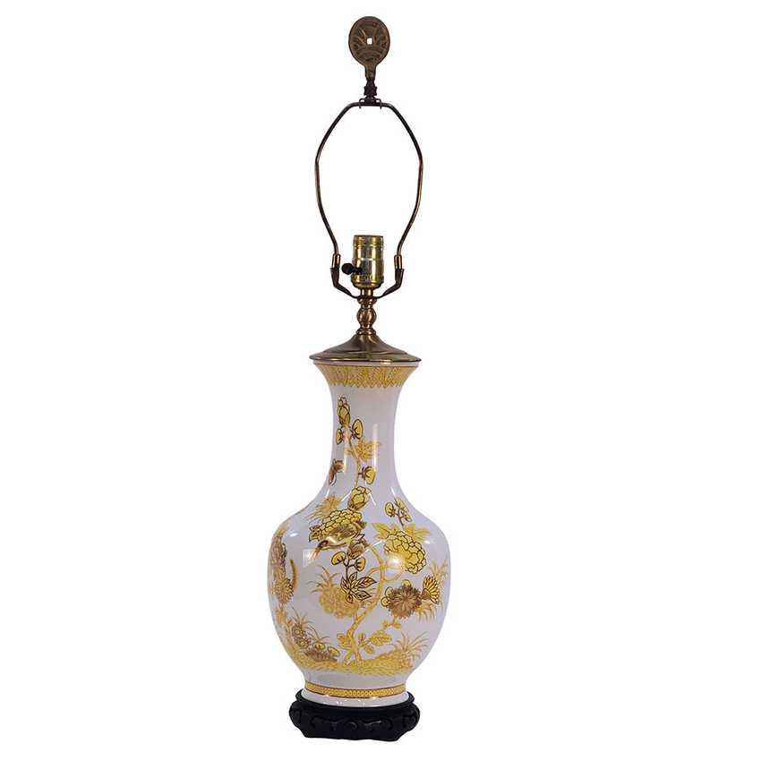 A vintage-style table lamp with a white porcelain vase-shaped body decorated with gold floral patterns, a gold-toned metal neck and shade, and a black base, shown against a plain white background.