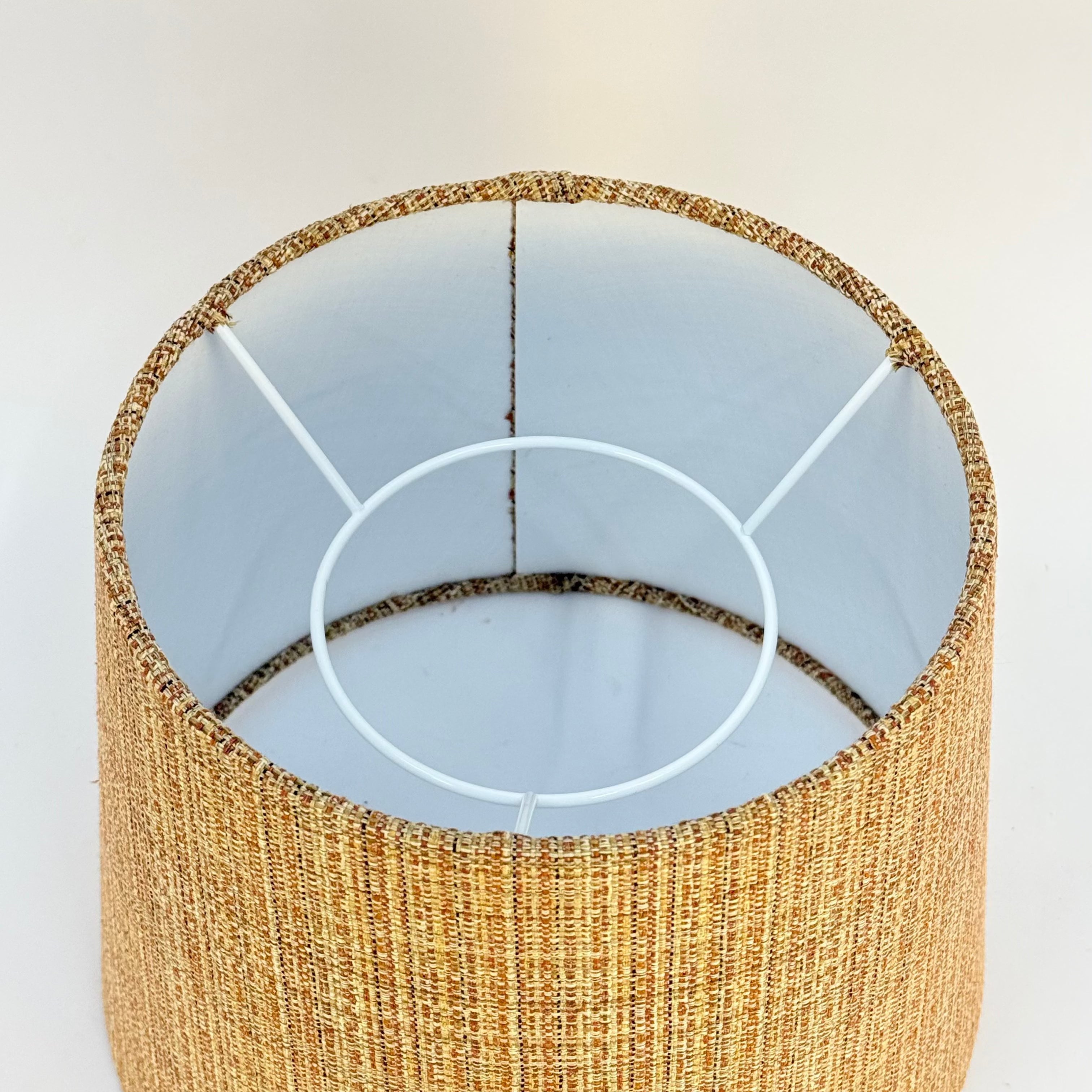 Close-up of a textured lampshade with a white interior on a light background