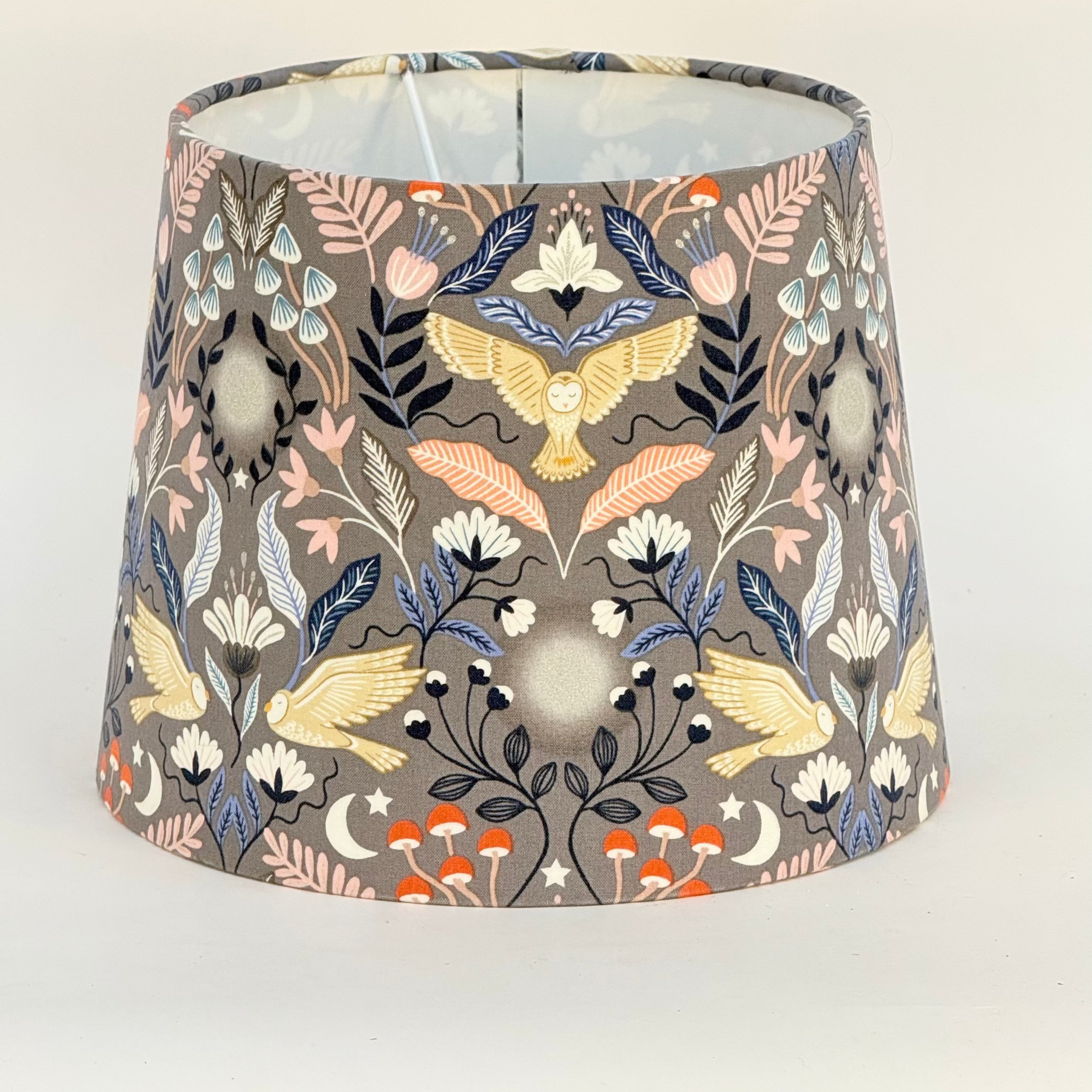 Decorative lampshade with bird and floral pattern on a plain background