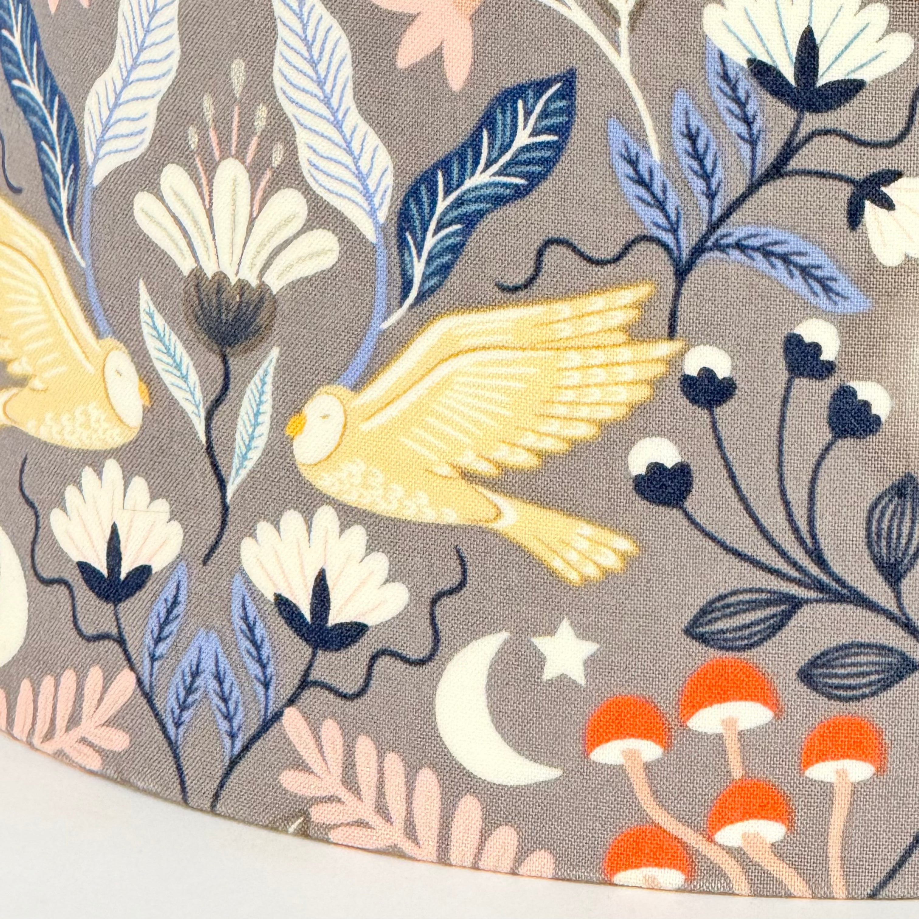 Fabric with embroidered birds, flowers, and mushrooms on a gray background