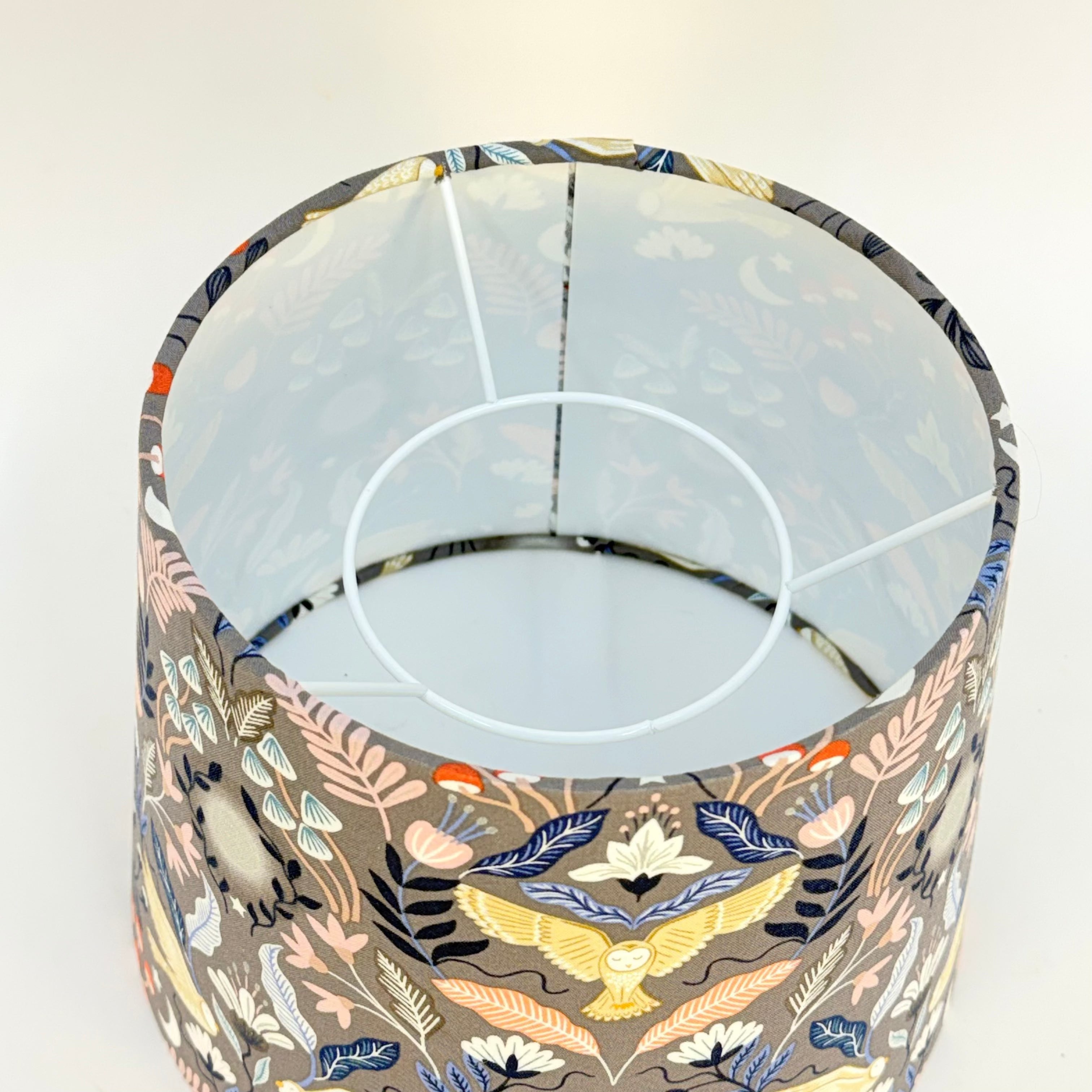 Decorative lampshade with floral and nature-themed pattern on a white background