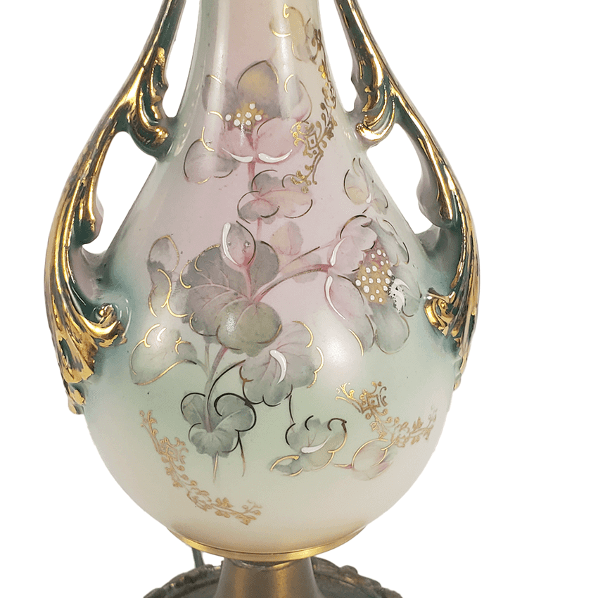 A close-up of an ornate ceramic vase with a pear-shaped body, featuring hand-painted pink and green floral motifs on a glossy cream background, accented with gold leaf detailing and decorative side handles.