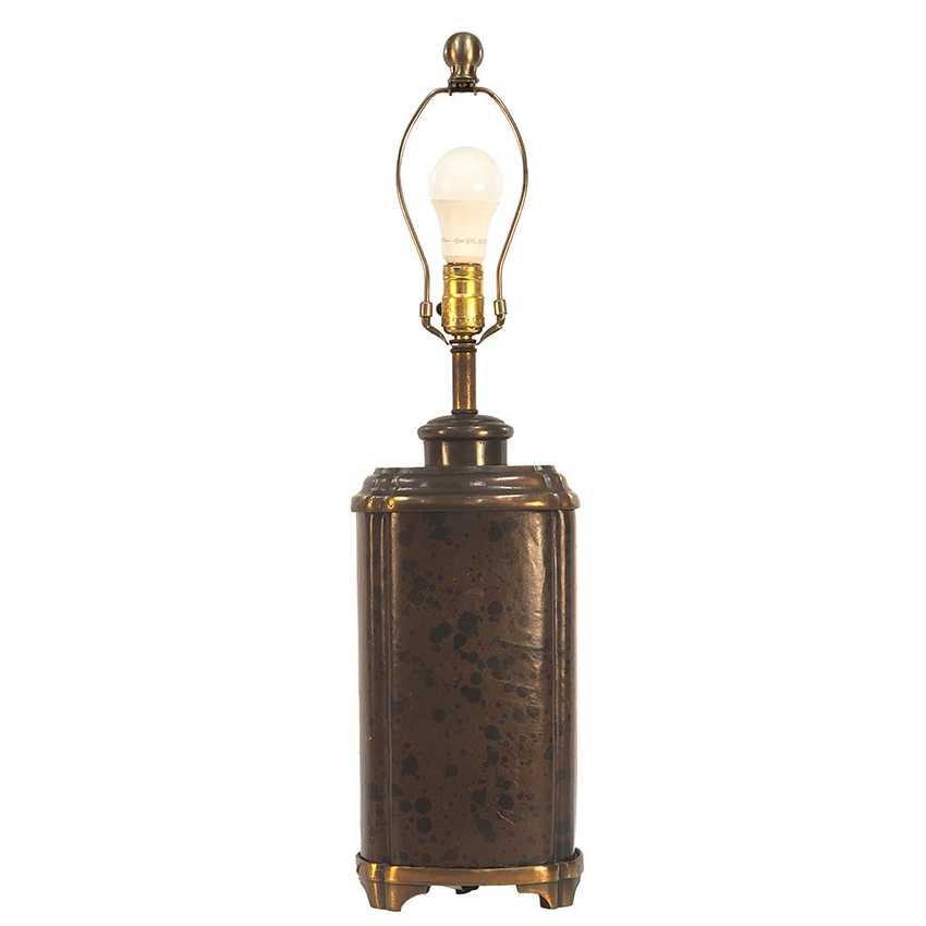A vintage-style table lamp with a textured, dark bronze cylindrical base and a brass-toned metal neck and light fixture, featuring a clear glass bulb, set against a plain white background.