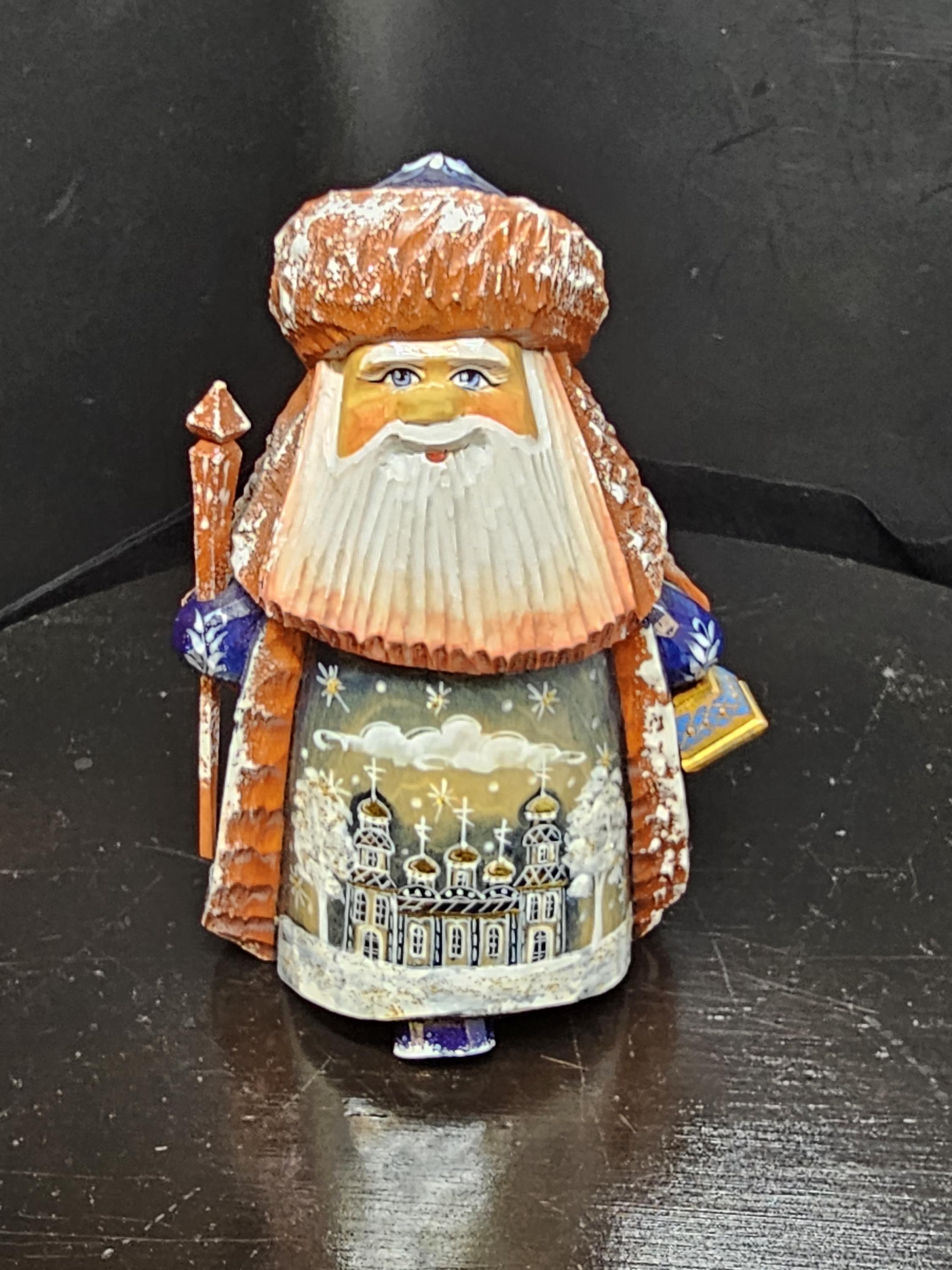 small hand carved wooden figuring of stout bearded older man with Russian Orthodox style building painted on robe in Palekh style