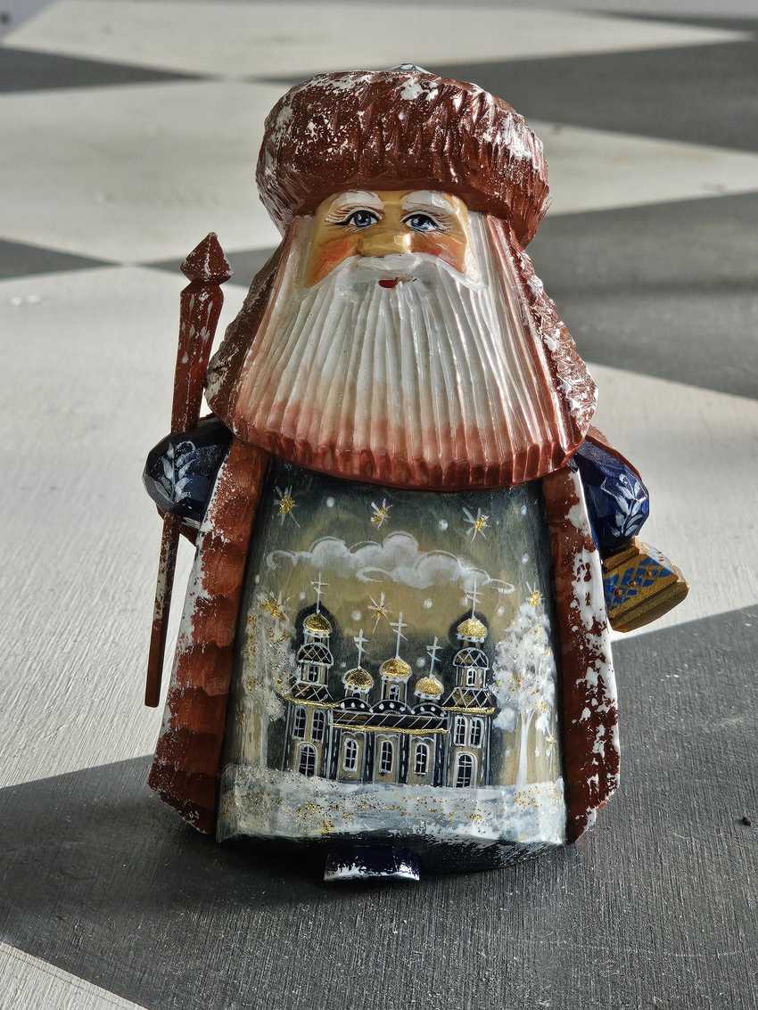 small hand carved wooden figuring of stout bearded older man with Russian Orthodox style building painted on robe in Palekh style