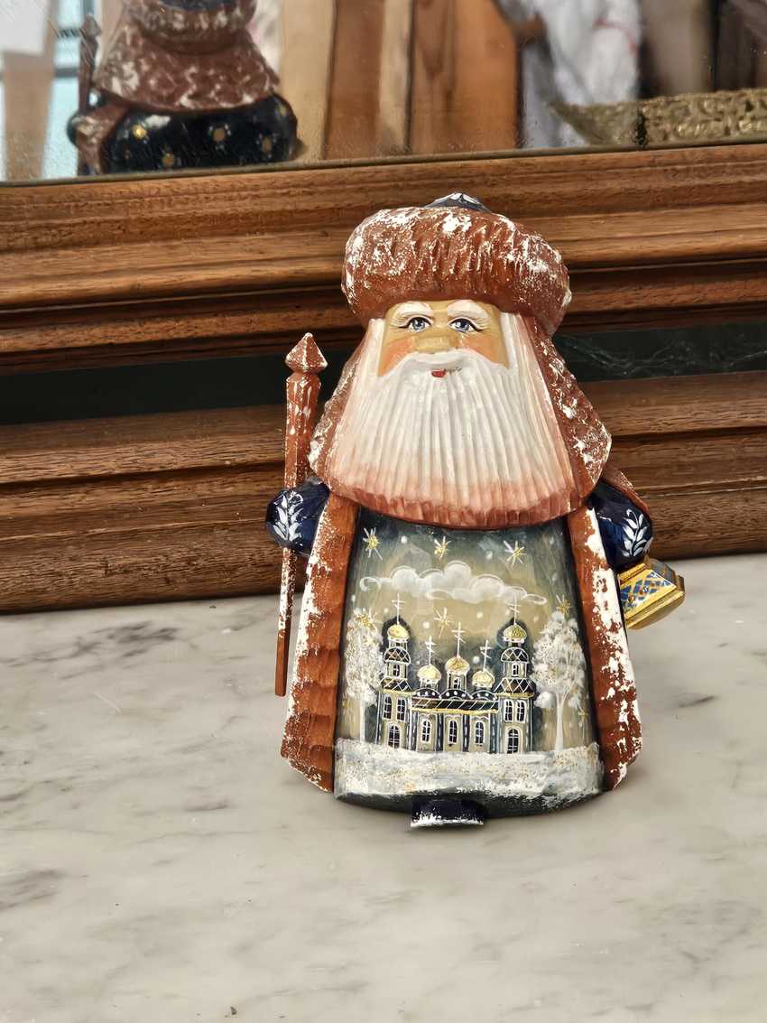 small hand carved wooden figuring of stout bearded older man with Russian Orthodox style building painted on robe in Palekh style
